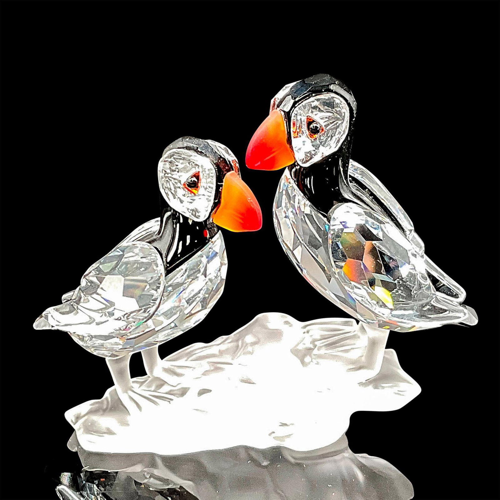 Swarovski Silver Crystal Figurine, Puffins: Clear crystal figural decorated with colored crystal in tones of black and orange in eye, beak, and head. The two birds stand atop frosted piece attached. Swarovski backstamp. 7621000008. This item ha