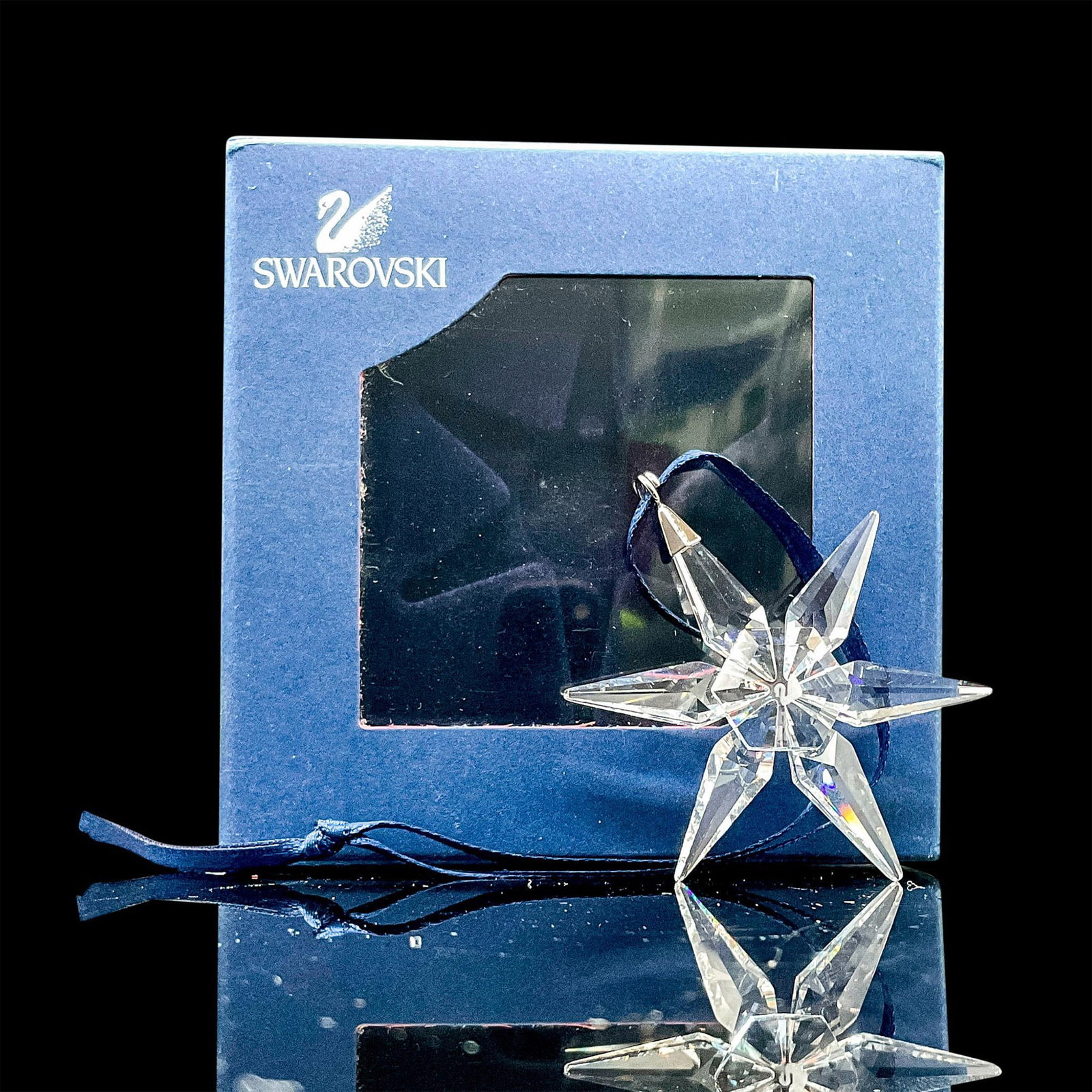 Swarovski Crystal Ornament, Little Star: A glittering faceted crystal ornament in the shape of a six-pointed star. Silver hook with dark royal blue ribbon. Swarovski acid mark to base. Original box included. Box dimensions: 3"L x 3"W x 1"H. 