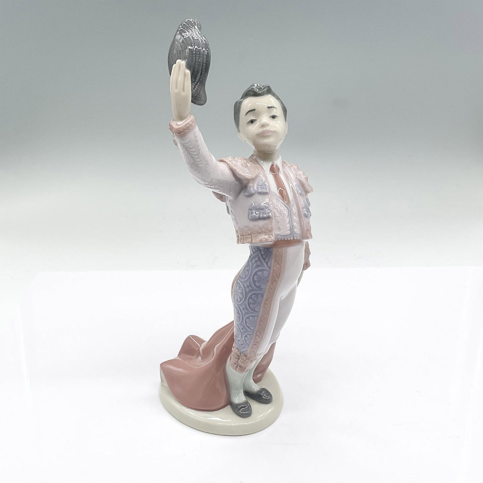 Lladro Porcelain Figurine, Little Matador: A young boy matador with hat off waving to the crowd. Gloss finish. Lladro backstamp. Issued: 20th century Dimensions: 4"L x 4"W x 9.5"H Manufacturer: Lladro Country of Origin: Spain