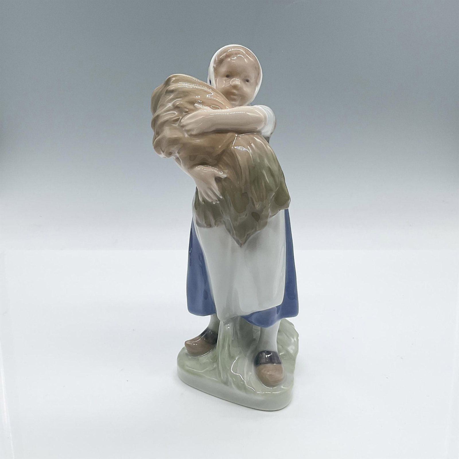Royal Copenhagen Figurine, Girl with Wheat 908: Glossy porcelain figure of a young farm girl tending to her duties with an armful of wheat. Royal Copenhagen backstamp. #908. Issued: 20th century Dimensions: 3"L x 3"W x 7.50"H Manufacturer: Royal Co