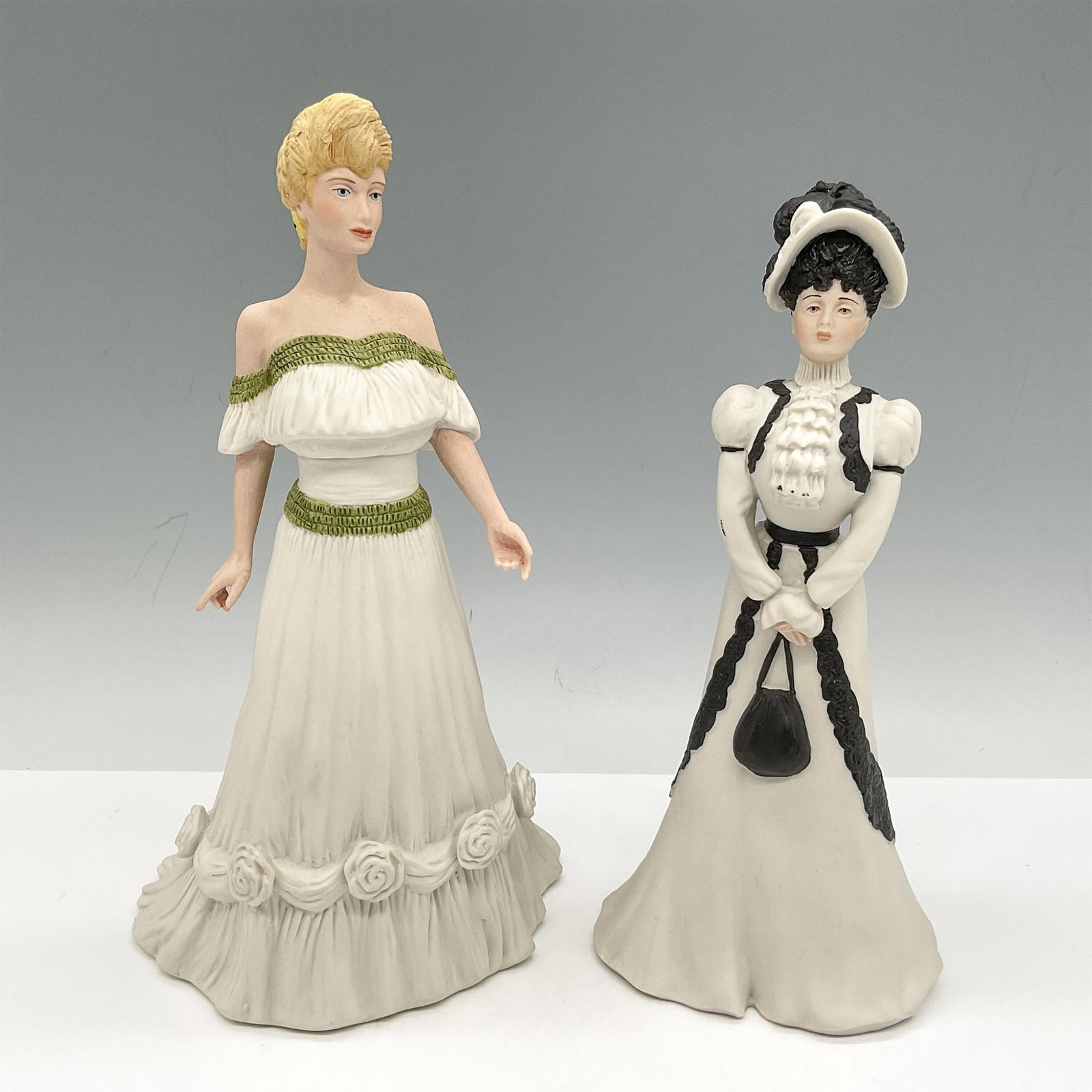 2pc Wedgwood Porcelain Figurines, Virginia + Caroline: Set includes Caroline from the Hyde Park Collection, designed in black and white and Virginia from the Age of Elegance collection designed in off the shoulder green and cream-colored gown. Wedgwood ba