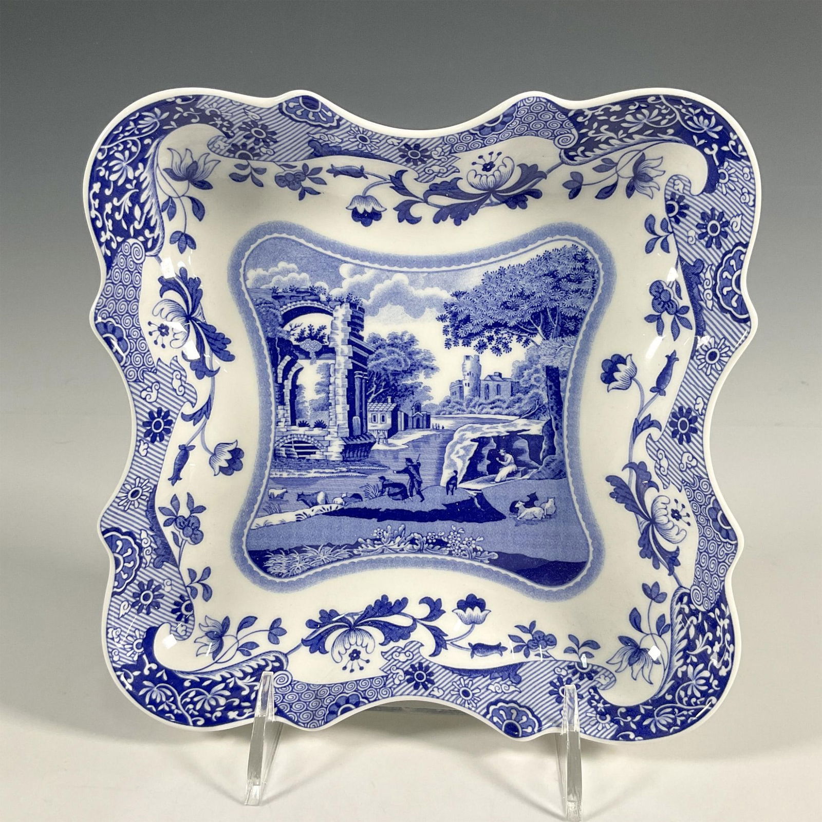 Spode Porcelain Devonia Tray, Blue Italian: A porcelain tray from the 250th Anniversary Collection. Blue transfer print decorations depicting Italian country scenes, intricate floral border. Spode backstamp. Dimensions: 7.75"L x 7.75"W x 1.5"H