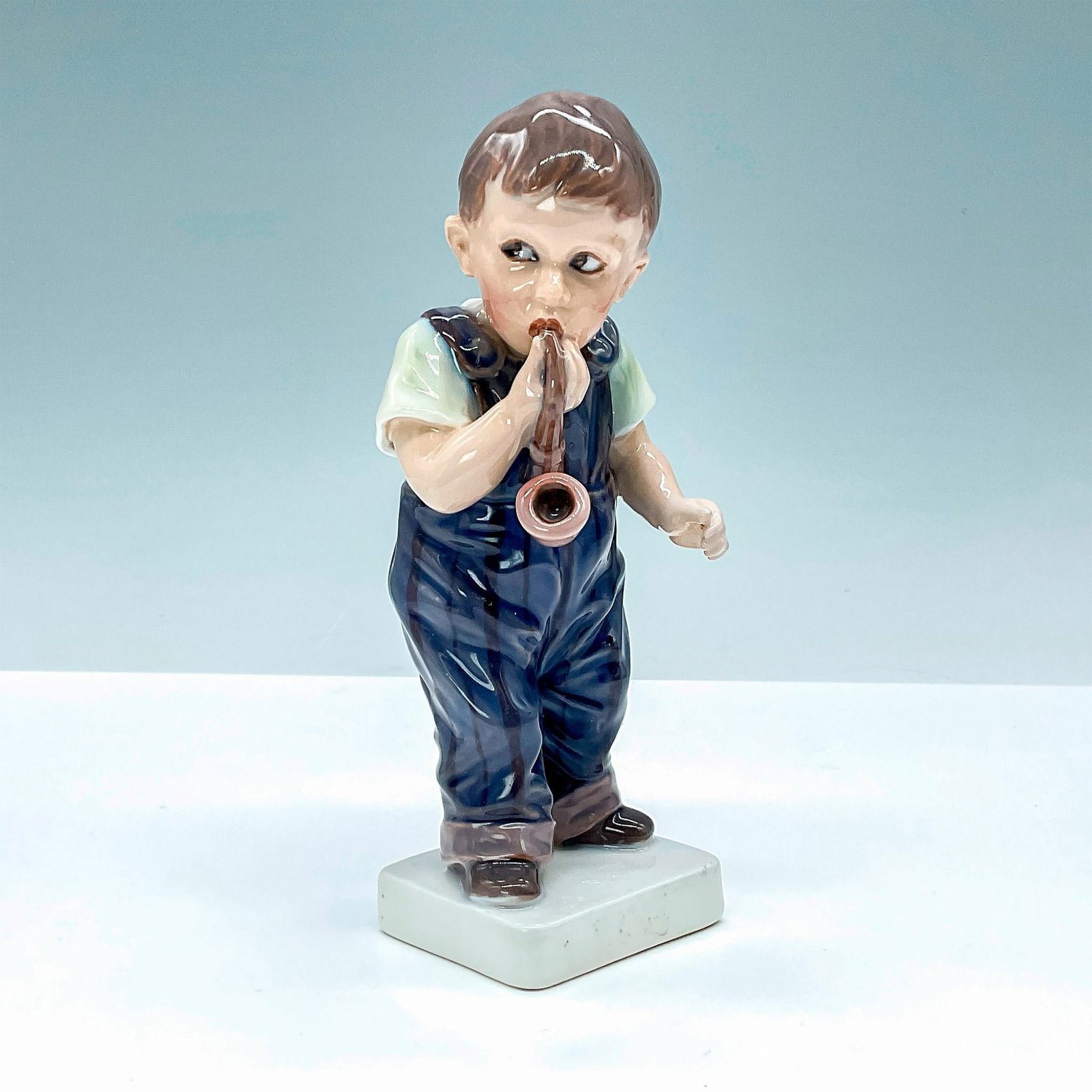 Dahl Jensen Figurine, Boy in Blue Overalls with Pipe 1027: Dahl Jensen figurine of boy with pipe. DJ Copenhagen backstamp. Artist: Jens Peter Dahl Jensen Issued: 20th Century Dimensions: 2.5"L x 2.5"W x 6.5"H Manufacturer: Dahl Jensen DJ Copenhagen Country o
