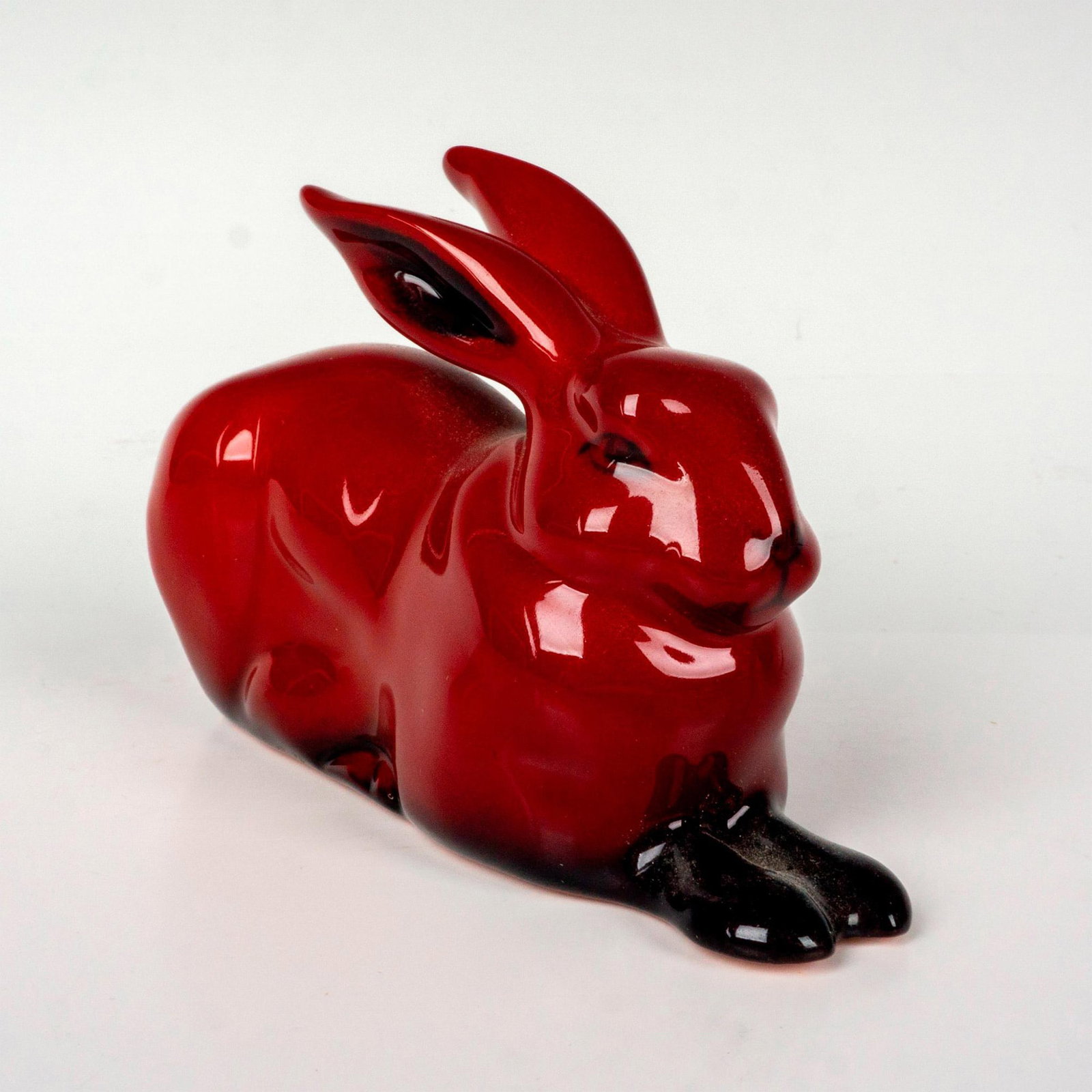 Royal Doulton Flambe Figurine, Crouching Hare HN2592: Style three, model number 1157. Rich red flambe glaze with black accents from firing process. Royal Doulton Flambe backstamp. Issued: 1945-1996 Dimensions: 1.75"L x 4.25"W x 2.75"H Manufacturer: Royal