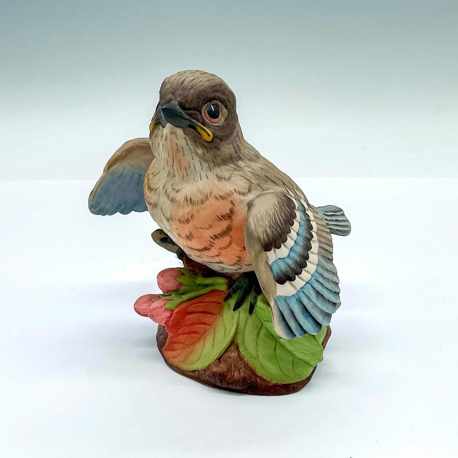 Boehm Porcelain Figurine, Fledging Bluebird: A naturalistic figure of a baby bluebird perched on top of pink flowers. Boehm backstamp. Artist: Edward Marshall Boehm Dimensions: 4.25"L x 4.25"W x 4.5"H Manufacturer: Boehm Country of Origin: Unite