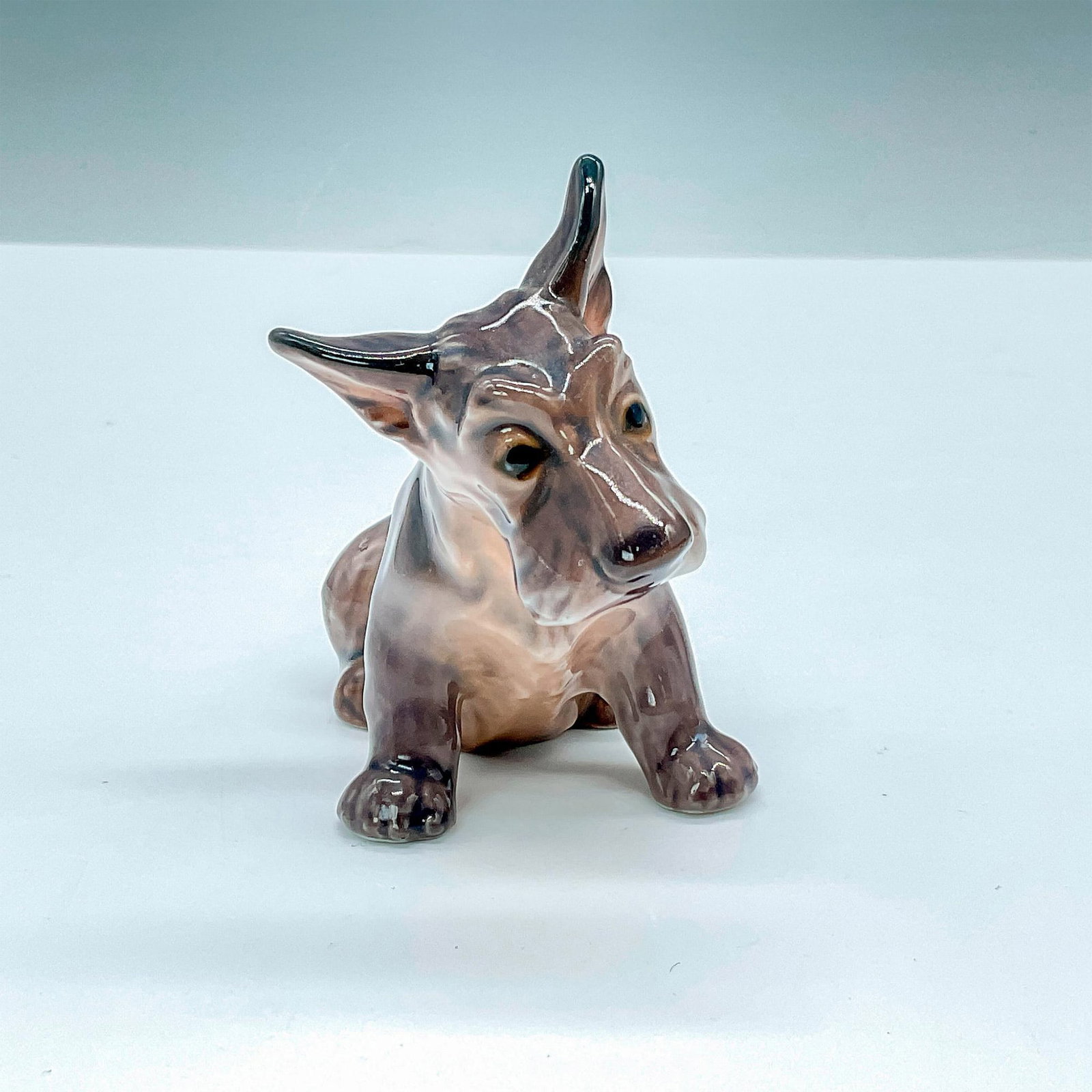 DJ Copenhagen Porcelain Figurine, Scottish Terrier Dog 1094: This Scottish Terrier pup figurine in all dark brown, features a gentle and sweet expression. DJ Copenhagen backstamp. Issued: 20th Century Dimensions: 4"L x 2.25"W x 3"H Manufacturer: Dahl Jensen DJ 