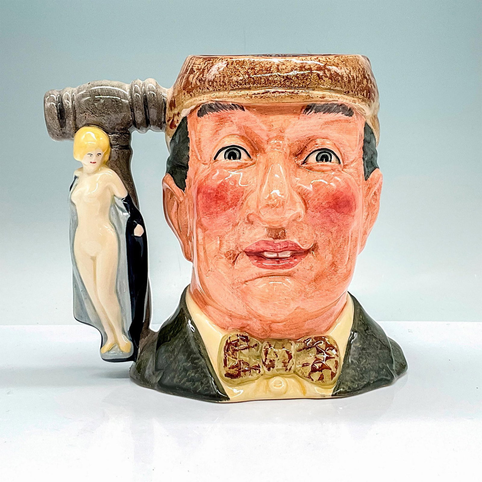 Auctioneer D6838 - Large - Royal Doulton Character Jug: Green coat and bow tie, light brown cap. Royal Doulton backstamp. Artist: Geoff Blower Issued: 1988 Dimensions: 6.25"H Edition Size: 5000 Manufacturer: Royal Doulton Country of Origin:</