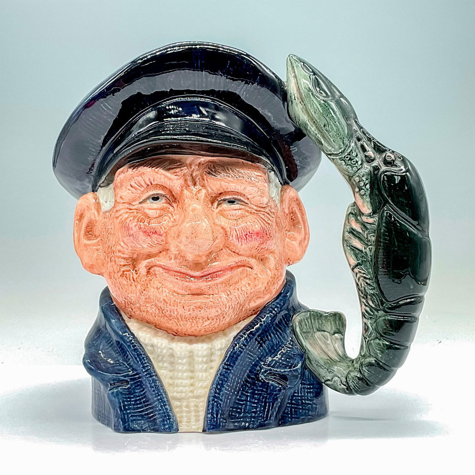 Lobsterman D6617 - Large - Royal Doulton Character Jug: Variation One: Dark blue jacket and cap, white fisherman's jersey. Royal Doulton backstamp. Artist: David B. Biggs Issued: 1968 - 1991 Dimensions: 7.5"H Manufacturer: Royal Doulton Country of Orig