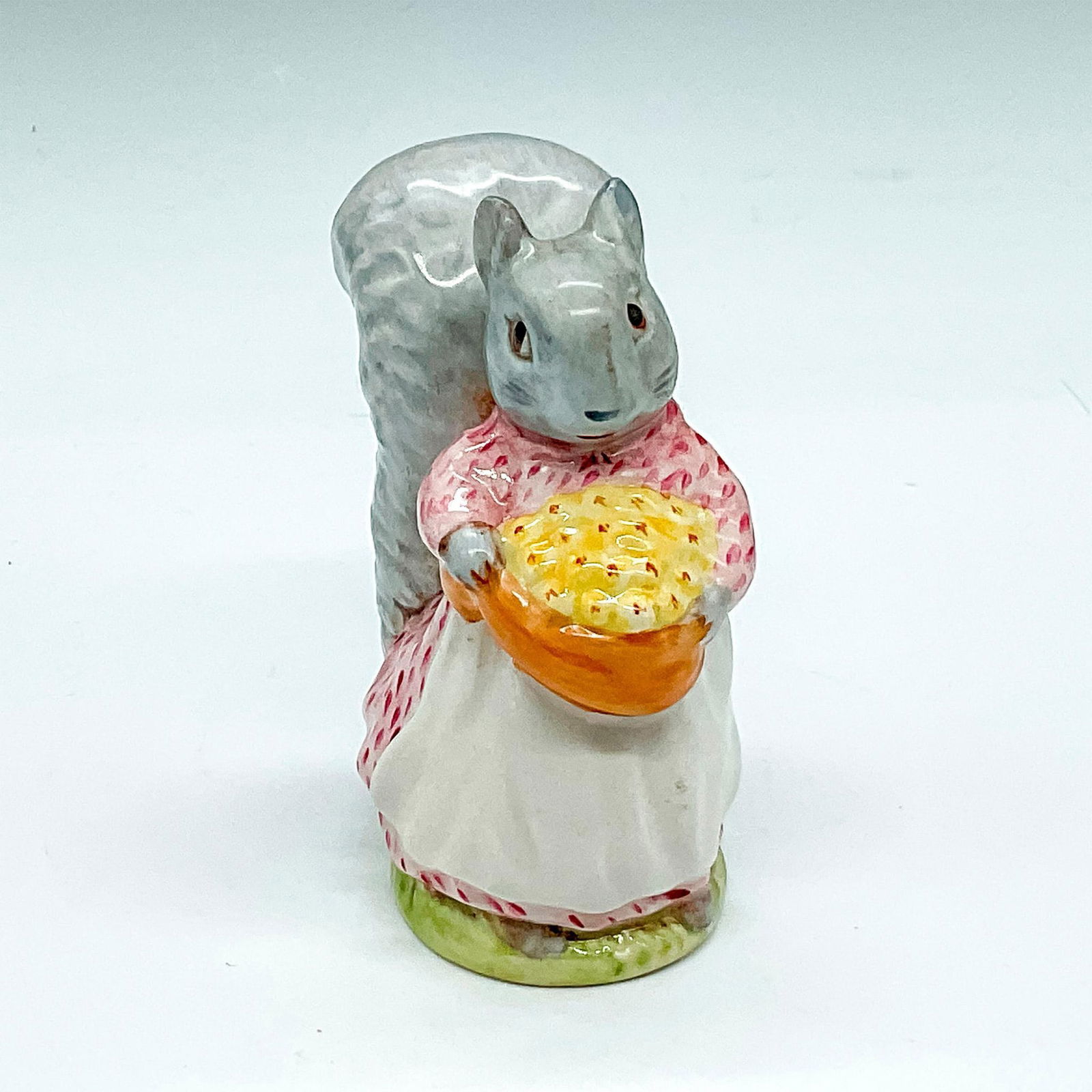 Beswick Beatrix Potter's Figurine, Goody Tiptoes: Colored in gray, pink and white holding basket with yellow nuts. Beswick Gold Oval backstamp. Artist: Arthur Gredington Issued: 20th century Dimensions: 2"L x 2.5"W x 3.5"H Manufacturer: Beatrix Potte