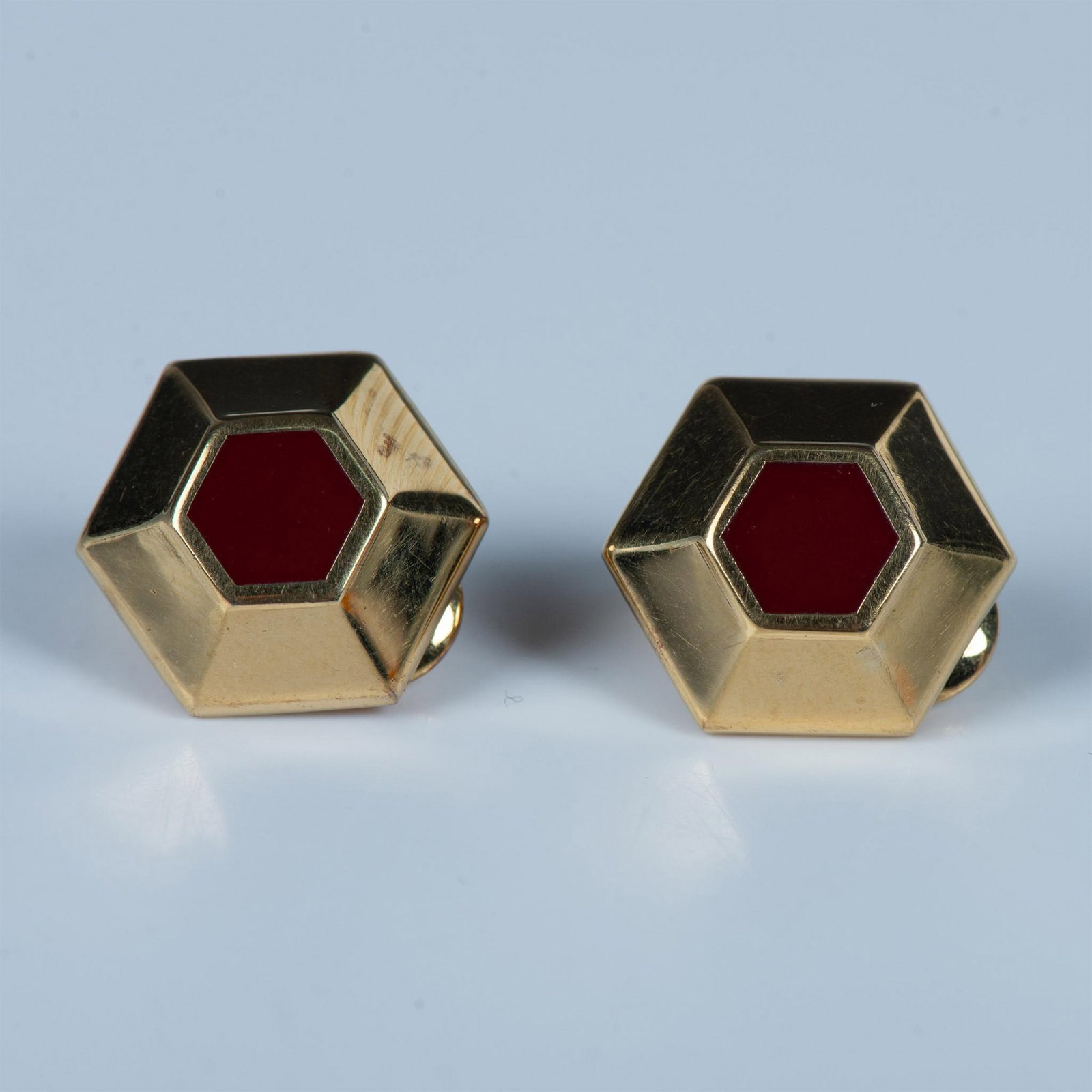 Monet Red Hexagon Gold Metal Clip-On Earrings: Gold tone hexagonal clip-on earrings with red centers. Monet hallmark stamped on the back clips. Dimensions: 0.75"L x 0.75"W Manufacturer: Monet Jewelry Country of Origin: United States