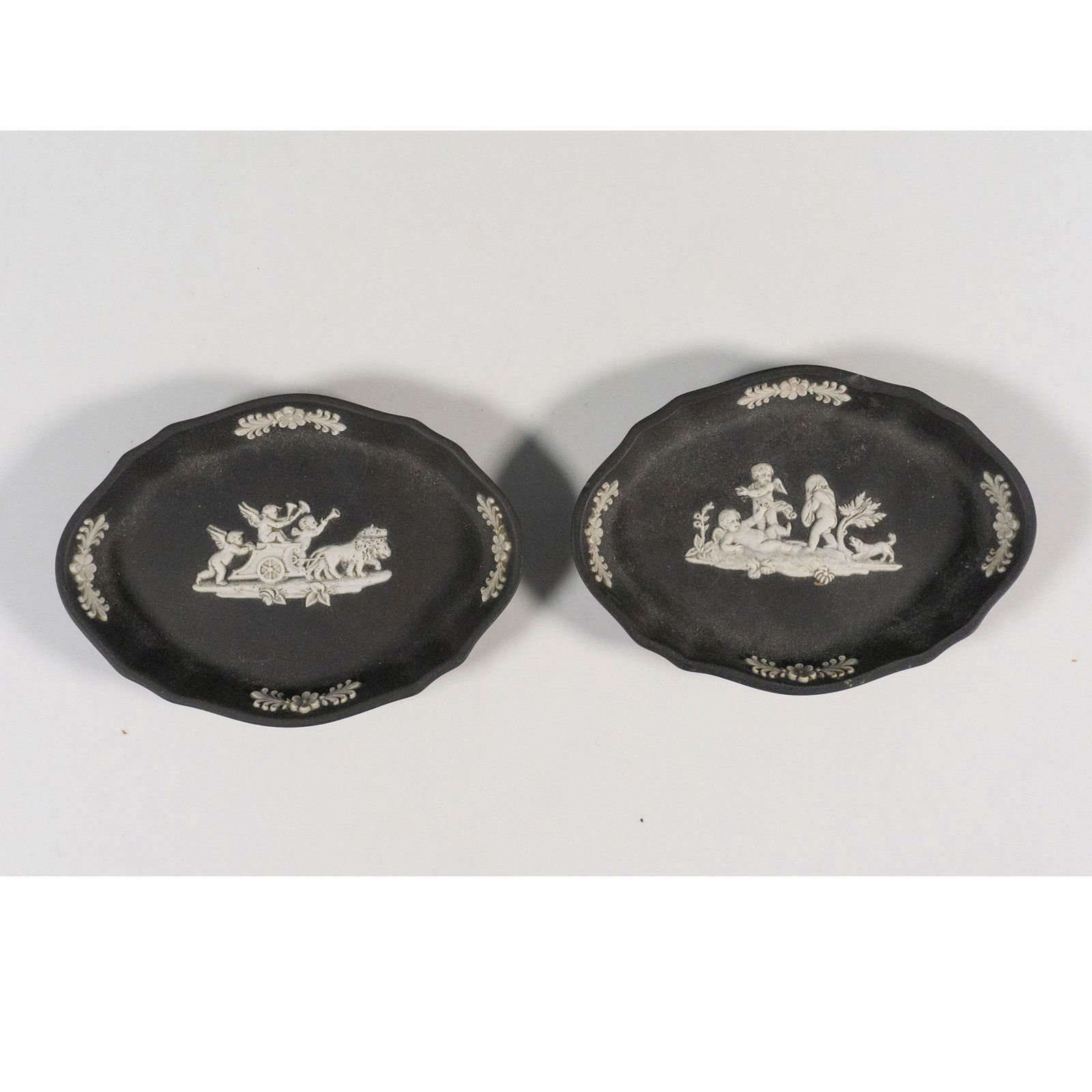 Pair of Wedgwood Black Jasperware Ring Trays: Black and white ring trays of oval shape decorated with neoclassical scenes, in relief. Wedgwood impressed backstamp. Dimensions: 4.25"L x 3.25"W x 0.75"H Manufacturer: Wedgwood Country of Origin: Eng