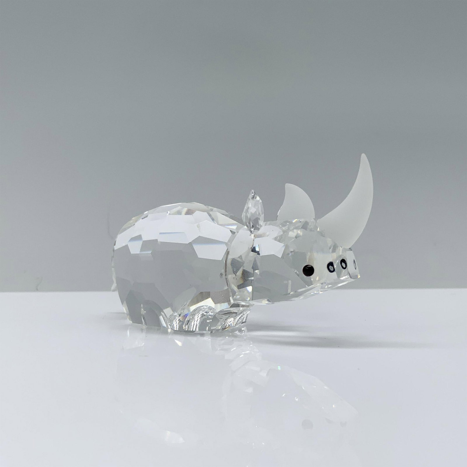 Swarovski Crystal Figurine, Rhinoceros 117900: A beautiful clear crystal rhinoceros with long hexagonal pattern cuts adorned with black crystal eyes and a frosted crystal horn. Swarovski backstamp. Artist: Adi Stocker Issued: 1988-1992 Dimensions: