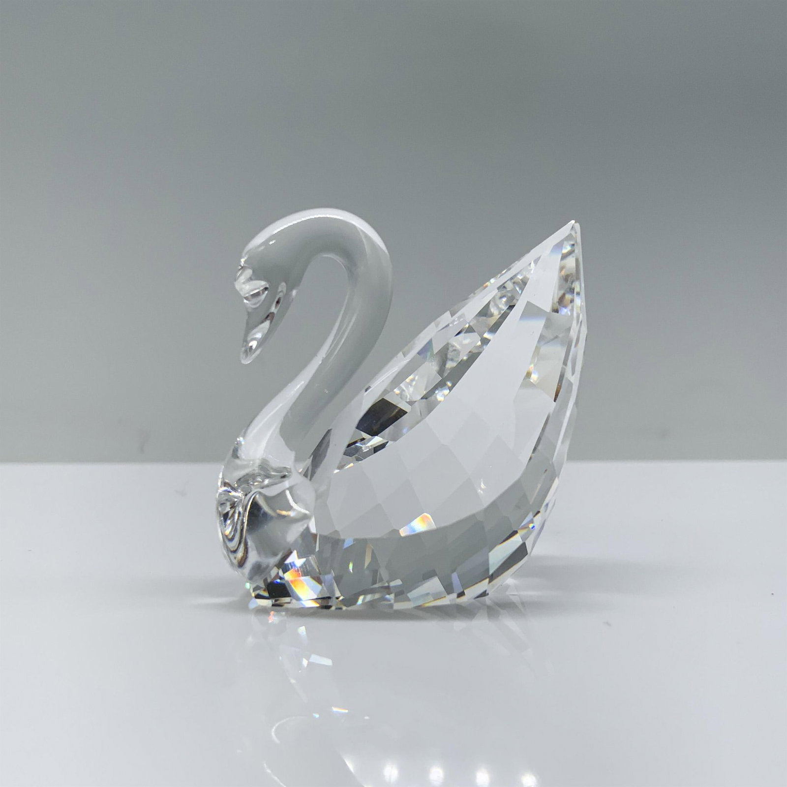 Swarovski Crystal Figurine, Swan: A mesmerizing clear crystal swan, artfully crafted to mirror the company's iconic logo, gracefully poised in a swimming position with a subtly curved neck. Swarovski backstamp. This item has its origi