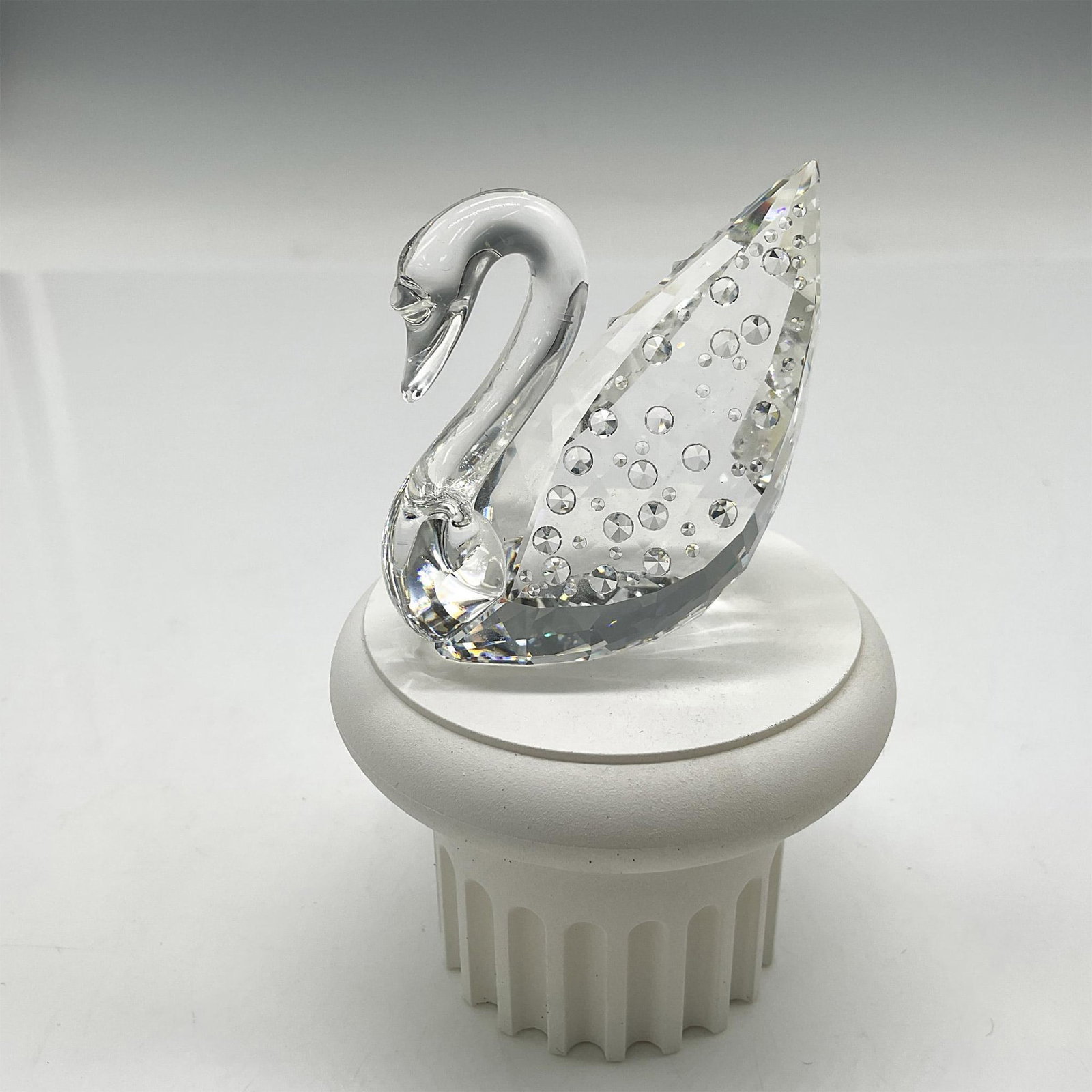 Swarovski Silver Crystal Figurine, 100th Anniversary Swan: Lovely swan with smooth crystal head and neck. Swans' wings are adorned with crystal rhinestones representing 1 for each year. Figurine comes with white pedestal base. Swarovski backstamp. 7633 100 00