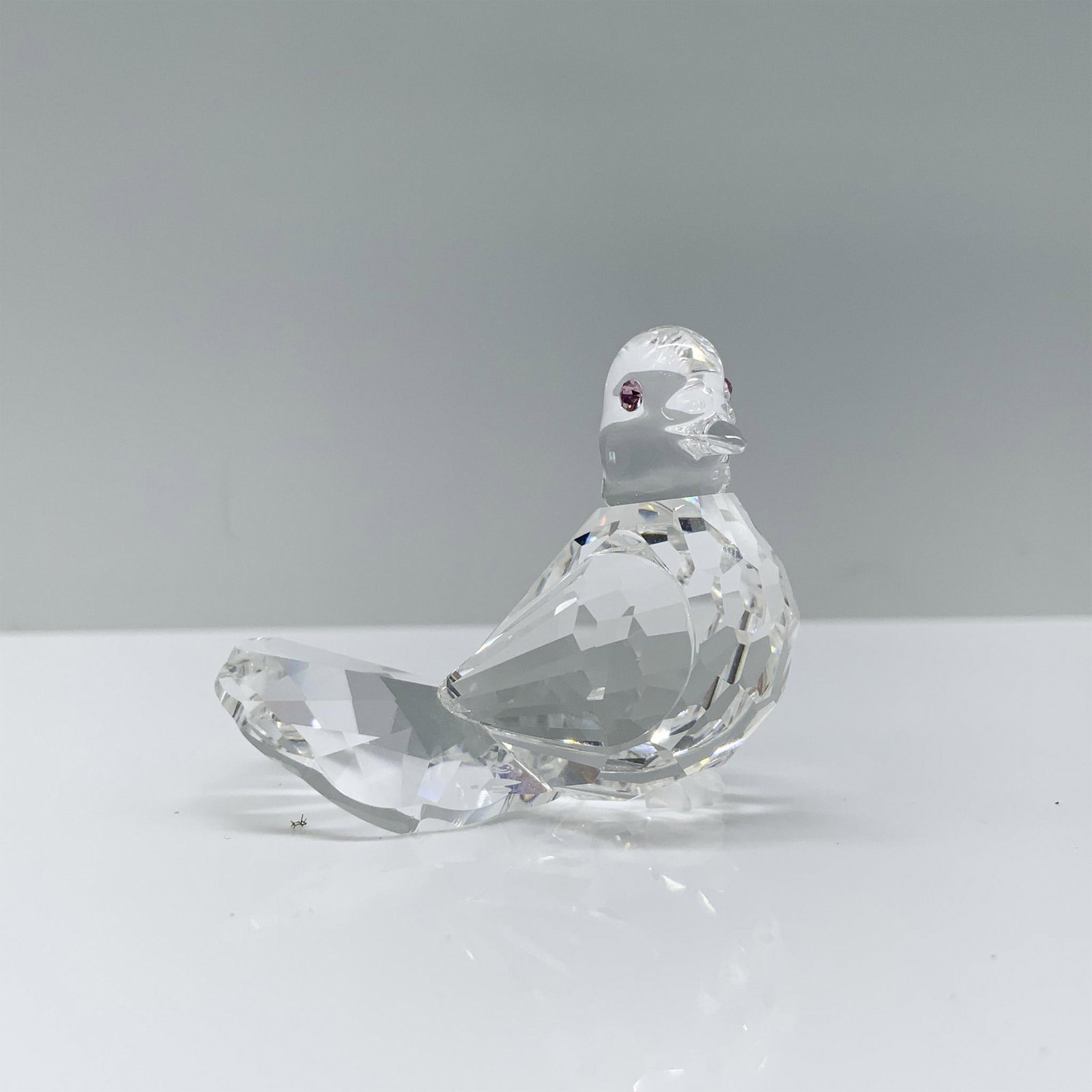 Swarovski Crystal Figurine, Dove 191696: A stunning clear crystal figurine of a dove in a seated position decorated with pink crystal eyes. Swarovski backstamp. This item has its original box. Dimensions of the box: 2.25"H x 3.25" dia. Artis