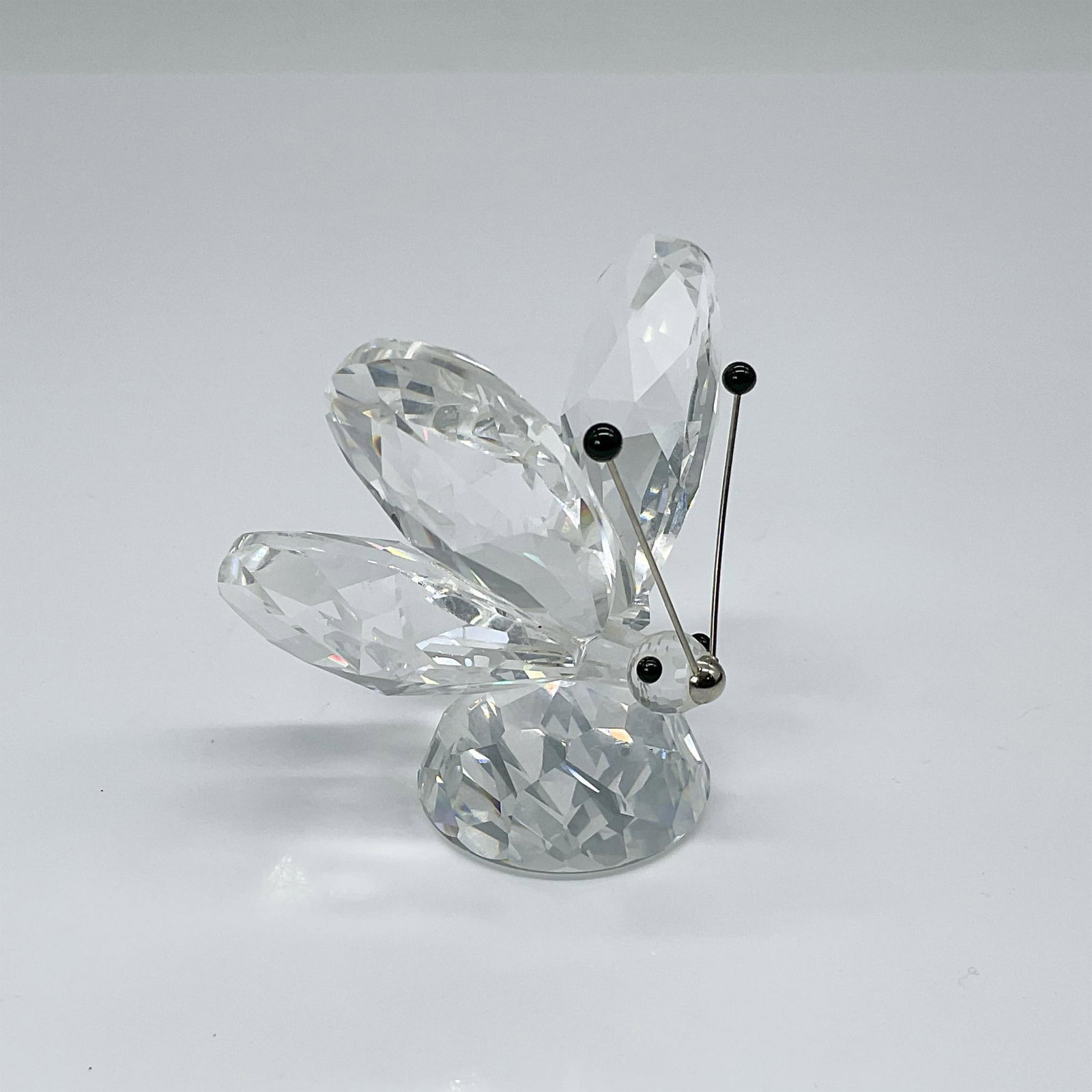 Swarovski Crystal Figurine, Butterfly w/Silver Antennae: Part of the In a Summer Meadow Collection, this piece features clear faceted wings, face, and body with black eyes, complemented by silver antennae topped with black crystal. Swarovski etched backstam