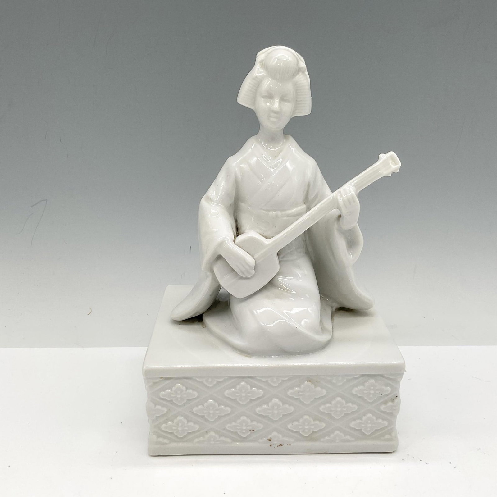 Vintage Porcelain Figurine, Geisha: Pure white porcelain figural sitting with musical instrument. Item originally created as a music box. Issued: 20th century Dimensions: 5"L x 3.5"W x 7.5"H