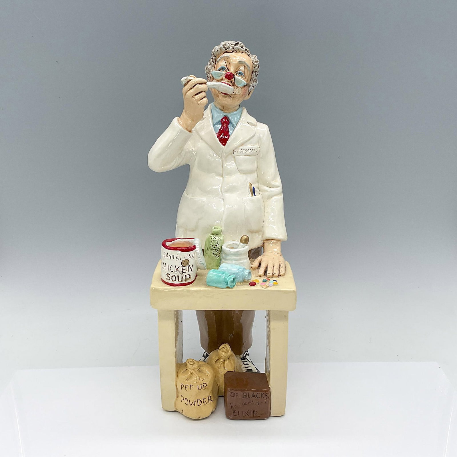 Judi's Pastime Ceramic Figurine, Pharmacist: Charming colorful handmade figurine depicting a Pharmacist Clown. Backstamp signed and carved on back. Issued: 1994 Dimensions: 4.75"L x 5.5"W x 13.25"H