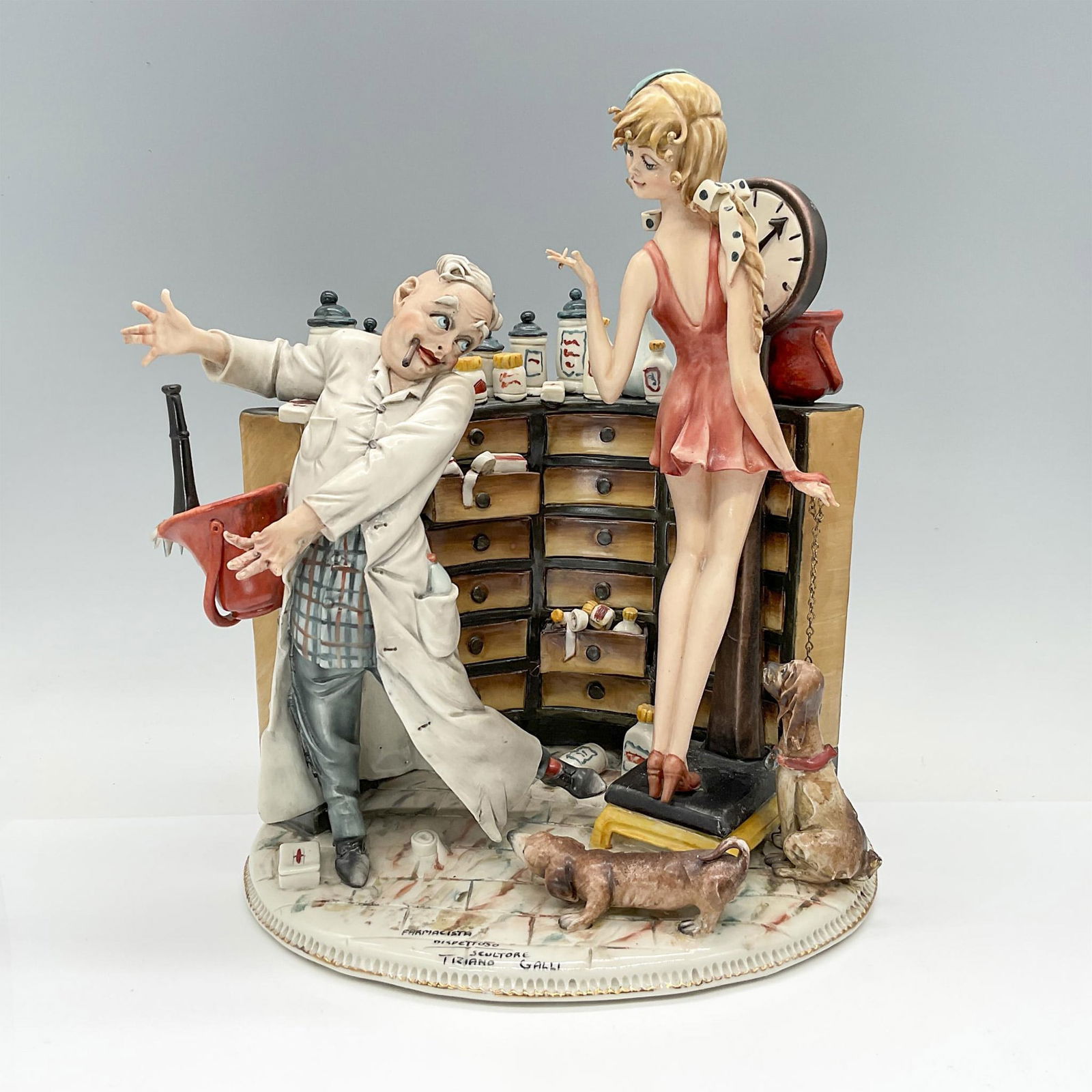 Tiziano Galli Porcelain Figural Scene, Farmacista Dispettoso: Lovely scene depicting a smitten pharmacist and a young lady in the pharmacy accompanied by two adorable dogs. The scene is highly detailed and realistically painted. Signed and titled. Crowned N mark