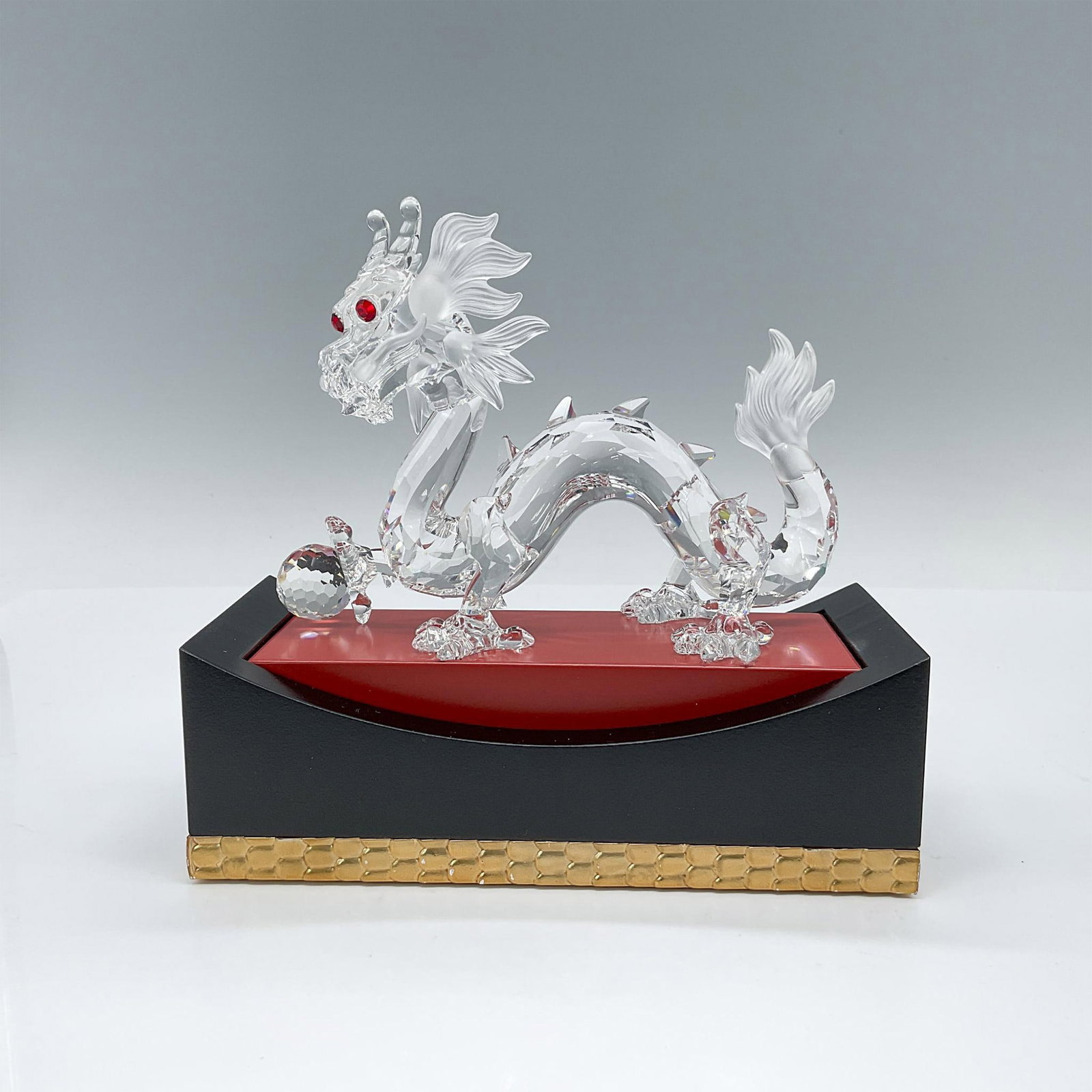Swarovski Crystal Figurine, Zodiac Dragon with Base: A magnificent Swarovski crystal figurine depicting a Chinese dragon gripping an orb in its right foot. Crafted with meticulous faceting, the dragon showcases exquisite, frosted crystal details and str