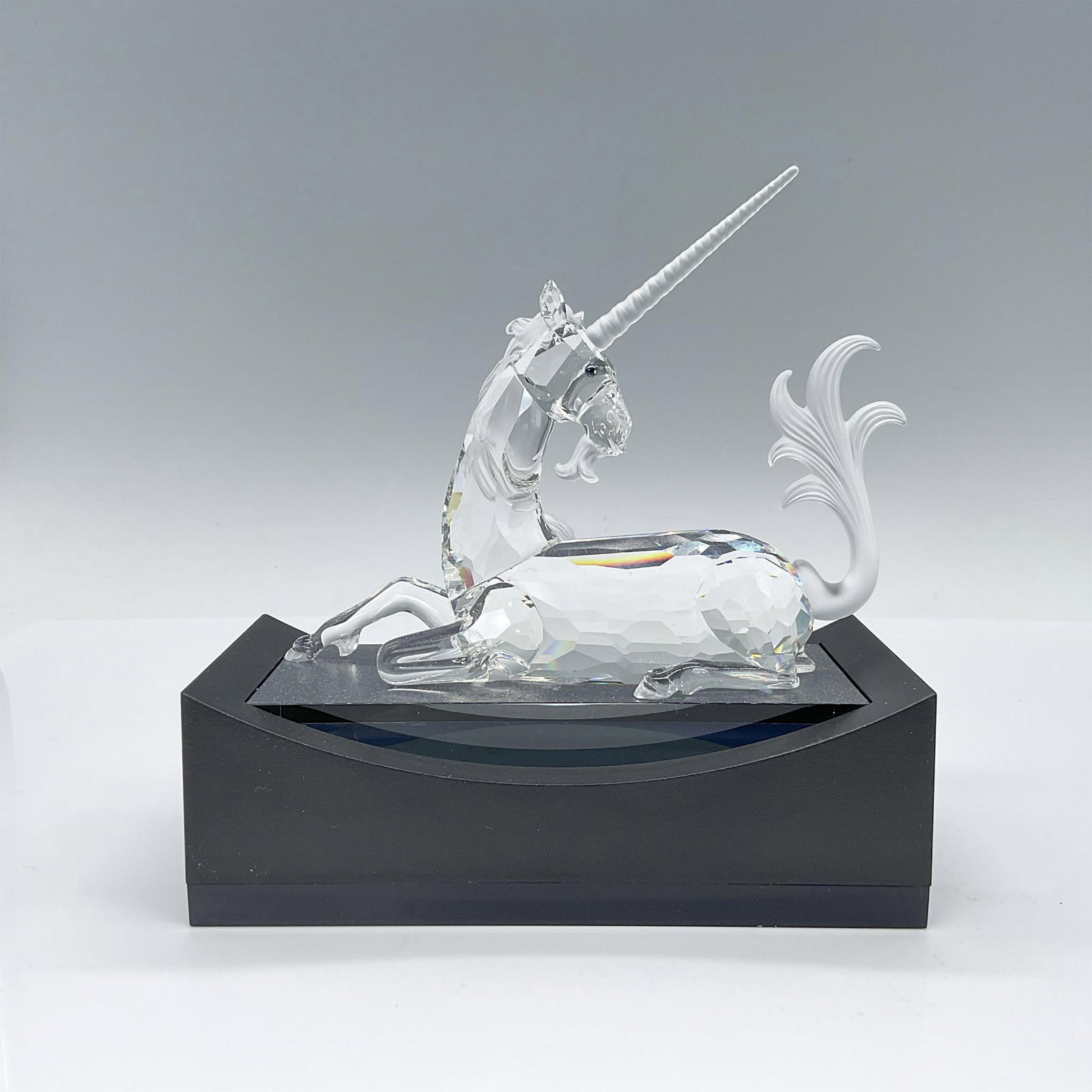 Swarovski SCS Crystal Figurine, Unicorn with Base: Part of the Fabulous Creatures trilogy, this unicorn figurine showcases a seated pose with its body crafted in clear crystal, while its mane, tail, horn, and beard feature a matte crystal finish. This