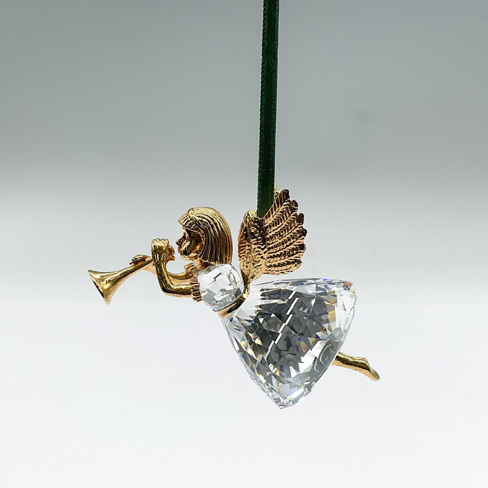 Swarovski Crystal Christmas Memories Ornament, Angel: Faceted crystal and gold ornament of a heralding angel. Swarovski mark. Includes original box: 4"L x 4"W x 3"H. Issued: 1997 Dimensions: 1.5"L x 1.75"W x 2.5"H Manufacturer: Swarovski Country of Origi
