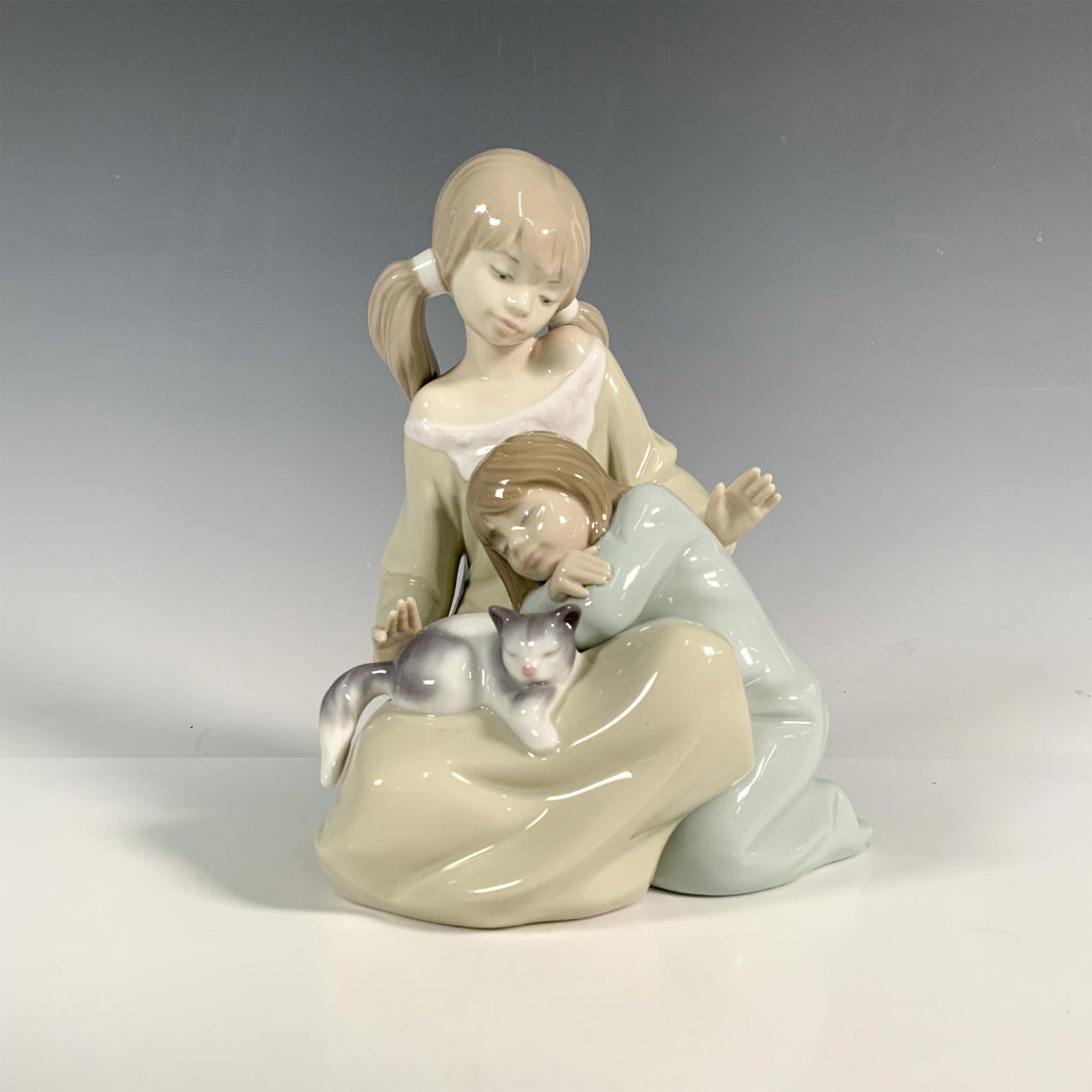 Little Sister 1001534 - Lladro Porcelain Figurine: Glossy finish; Lladro backstamp. Includes original box. Dimensions of the box: 12.5"L x 7.5"W x 6"H. Artist: Francisco Catala Issued: 1988-2005 Dimensions: 7.25"H x 5.25"W Manufacturer: Lladro Cou