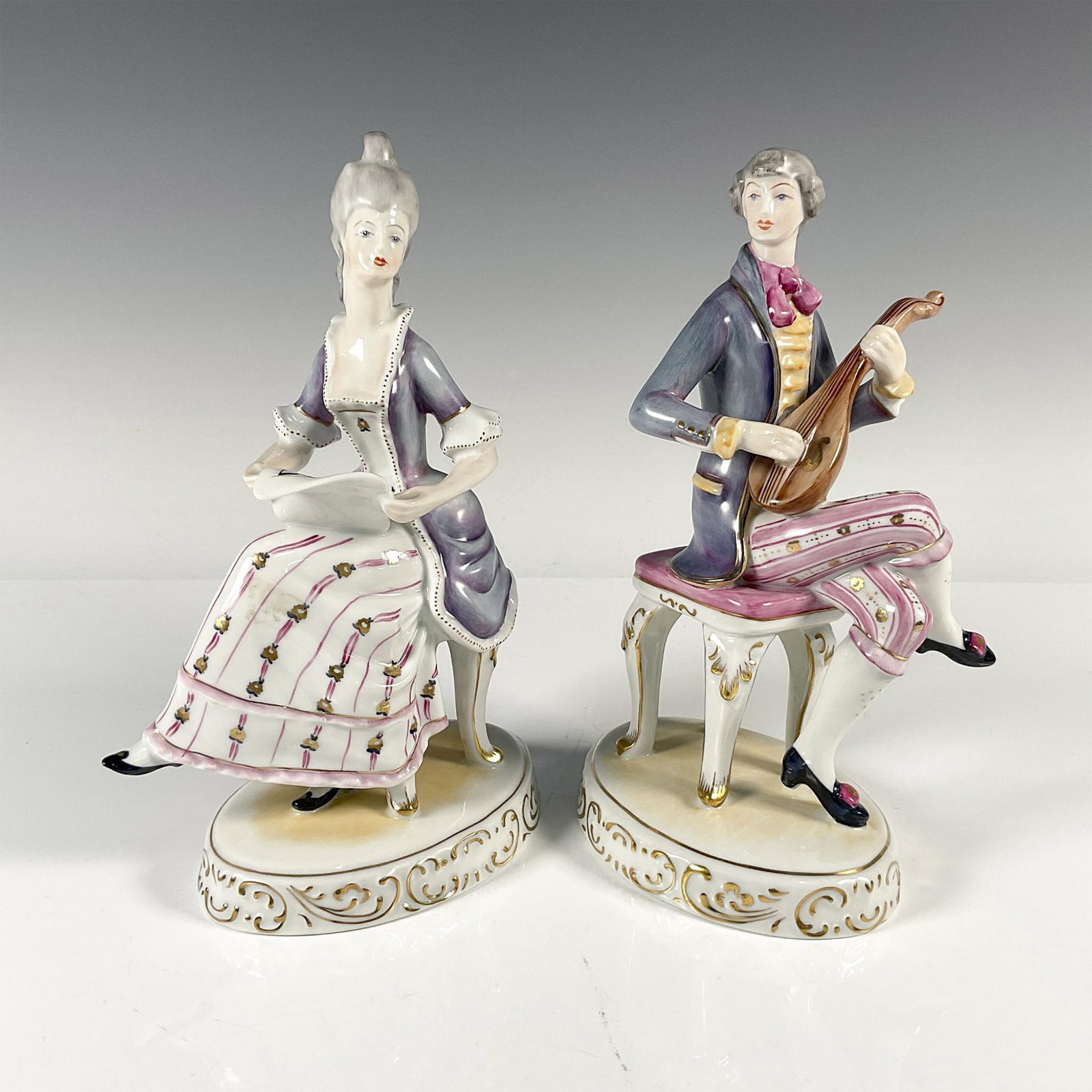 2pc Hollohaza Porcelain Figurines, Musical Couple: Seated couple rehearsing music. Gloss finish. Hollohaza Hungary 1834 backstamp in green Issued: 20th century Dimensions: 6"L x 3.75"W x 9"H Manufacturer: Hollohaza Country of Origin: Hungary