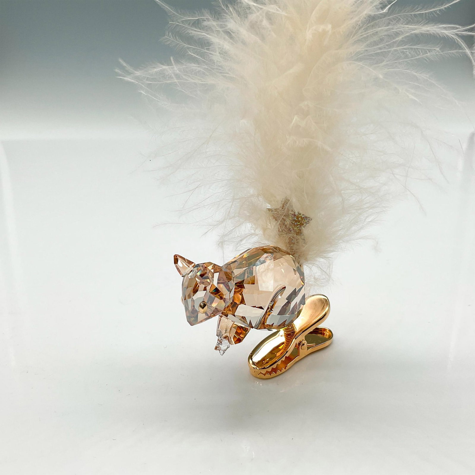 Swarovski Crystal Ornament, Winter Squirrel: Part of the Merry Christmas theme. Figural is designed in amber crystal holding a star with his crystal bushy feather tail attached to gold toned clip. Swarovski impressed mark. 1006040. This item has