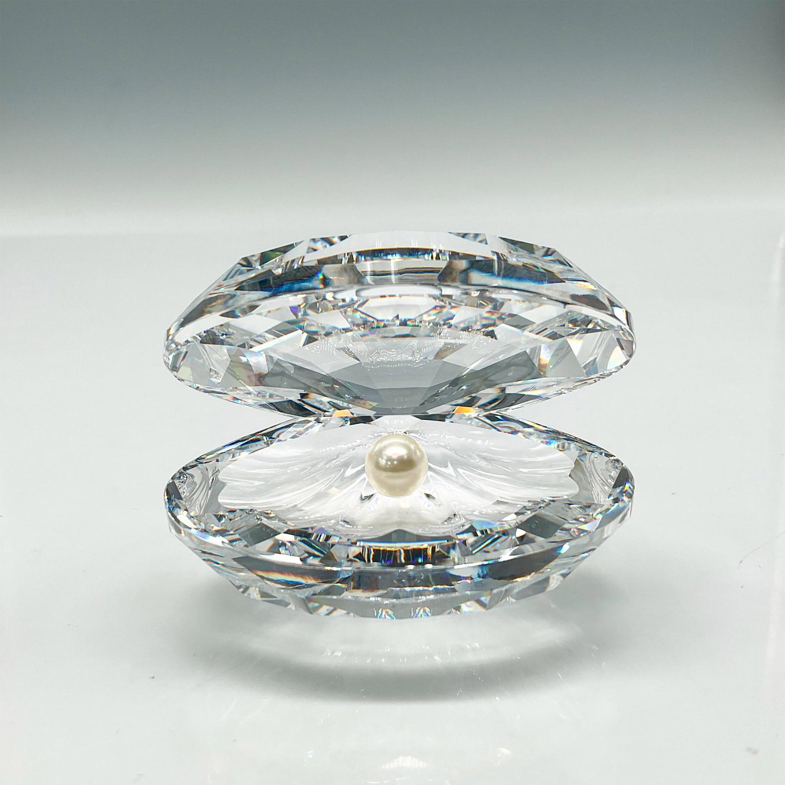 Swarovski Crystal Figurine, Clam with Pearl: Open clear crystal with pearl at center. Swarovski backstamp. This item has its original box: 5"L x 5"W x 3.25"H. Certificate of Authenticity included. Artist: Michael Stamey Issued: 1988 - 2017 Dimen