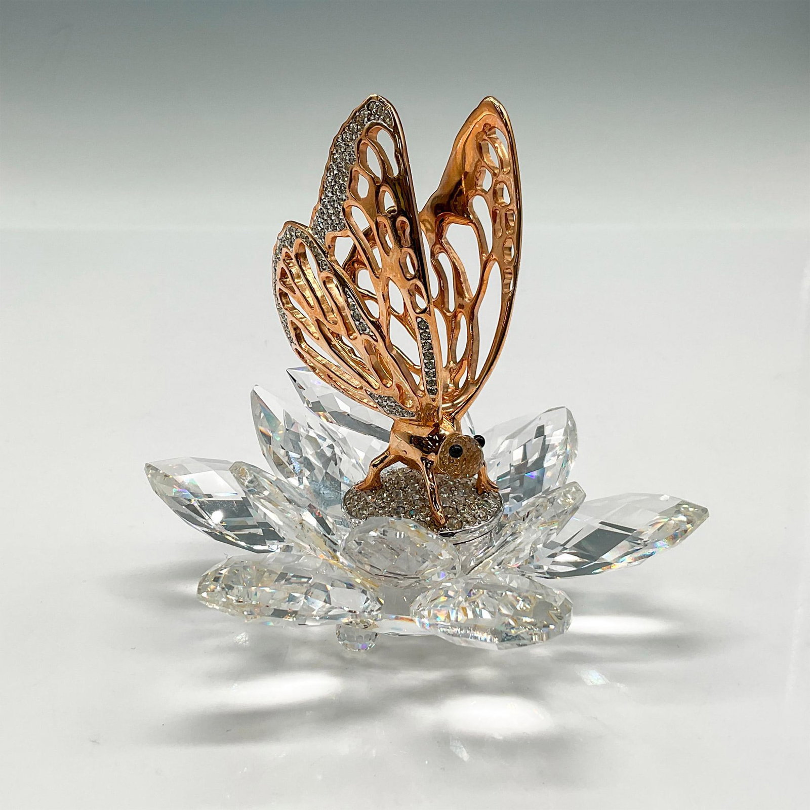 Swarovski Silver Crystal Figurine, In Flight Butterfly: Figurine is inspired from nature and has a body crafted from gold toned rhodium with intricate details and embellished with glistening crystals in the wings. Figural is perched on crystal flower looki