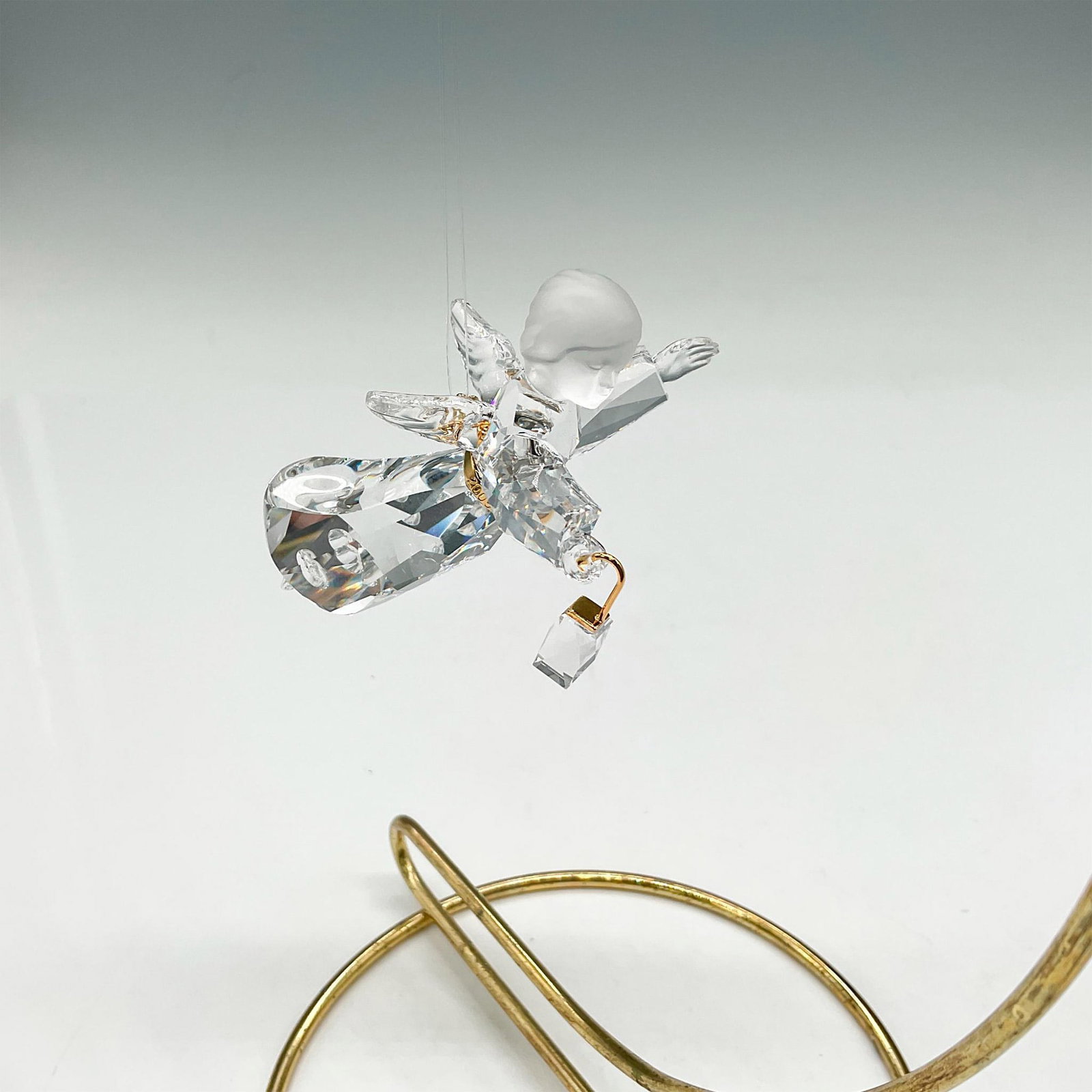 Swarovski Crystal Ornament, Angel Holding Lantern: This limited-edition crystal was created for 2005 only and is part of the Crystal Seasons group. Clear faceted crystal body with satin crystal head and gold toned rhodium sash. Swarovski impressed mar