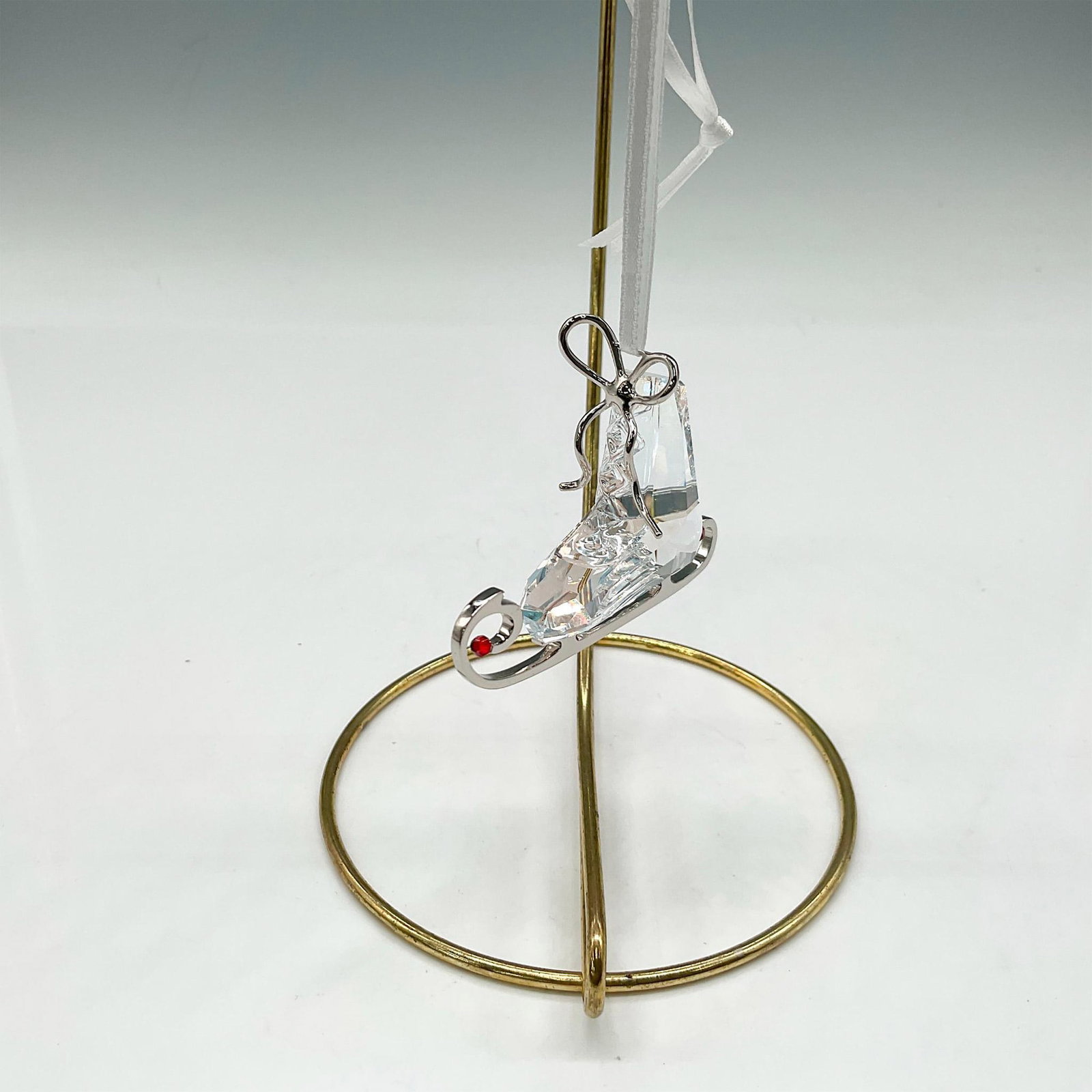 Swarovski Crystal Ornament, Winter Skate: Part of the Merry Christmas theme group. Created from Moonlight crystal and features Light Siam crystal beads mounted at ends of blade. The rhodium laces and blade gleam against the crystal on this un