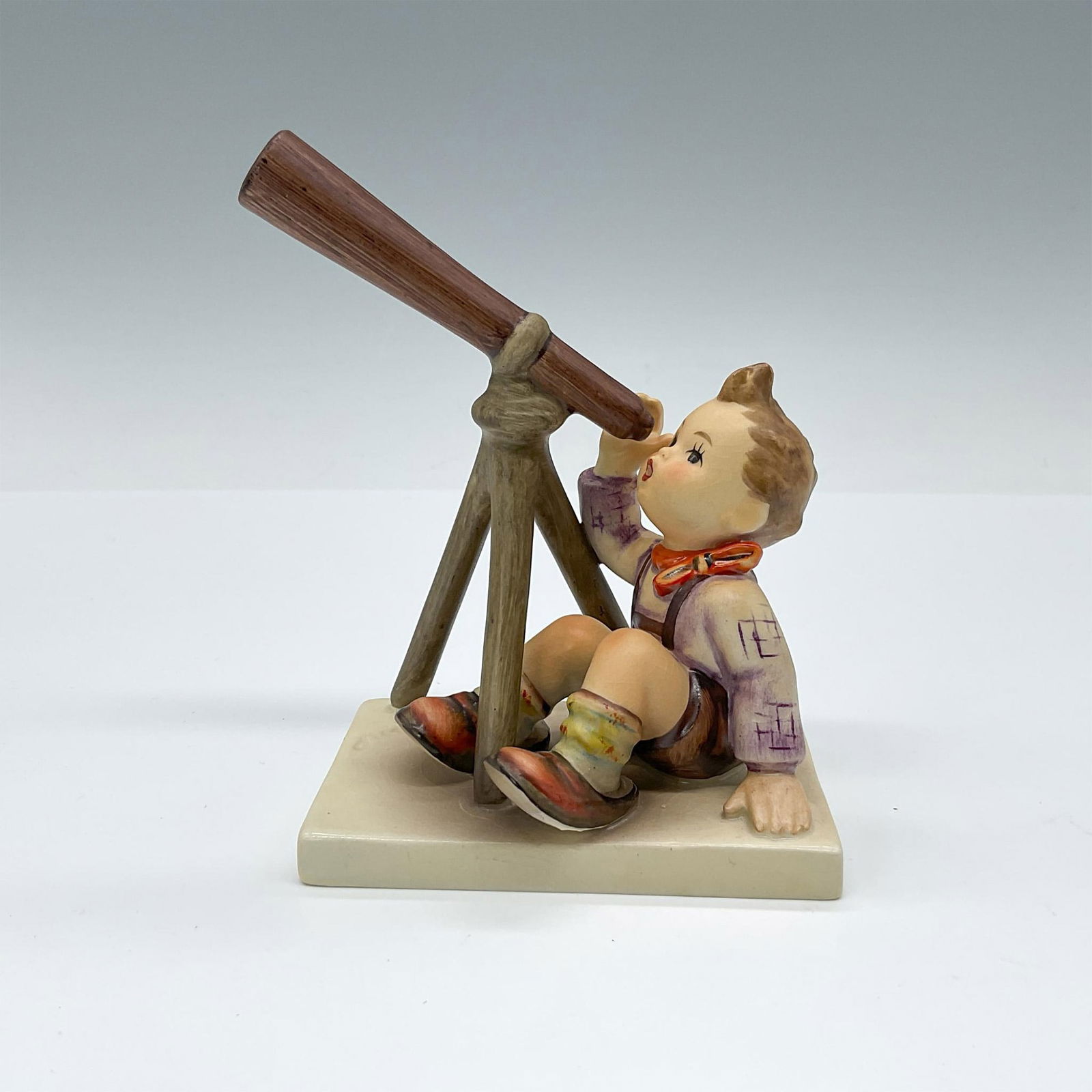 Star Gazer HUM 132 - Goebel Hummel Figurine: Matte porcelain figurine capturing a boy's wonder through a telescope. Goebel TK5. Issued: 1972-1979 Dimensions: 4"L x 2.75"W x 4.75"H Manufacturer: Goebel Hummel Country of Origin: Germany