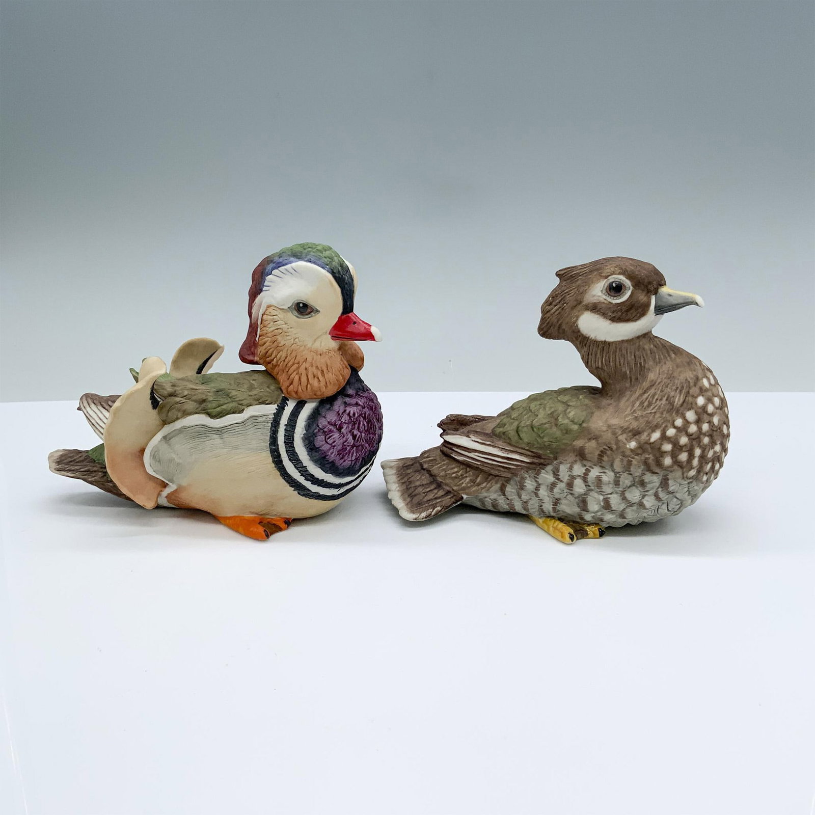 Pair of Boehm Porcelain Mandarin Duck Figurines 40106: Bisque porcelain hand painted by the Boehm Artisans. The vividly colored male measures 5.5"L x 2.75"W x 4.25"H. The detailed female measures 5.25"L x 2.75"W x 4"H. Boehm backstamps on the bottoms. Iss