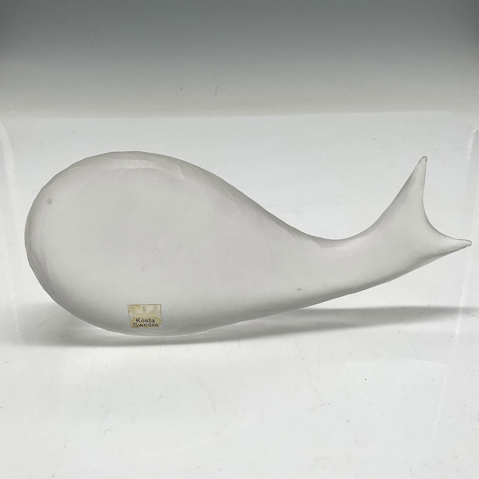 Kosta Boda Art Glass Whale, Signed: Carved and shaved glass figural. Kosta Boda sticker. Signed by Artist. 95916. Artist: Vicke Lindstrand Issued: 20th century Dimensions: 6.75"L x 1.25"W x 3"H Manufacturer: Kosta Boda Country of Origi