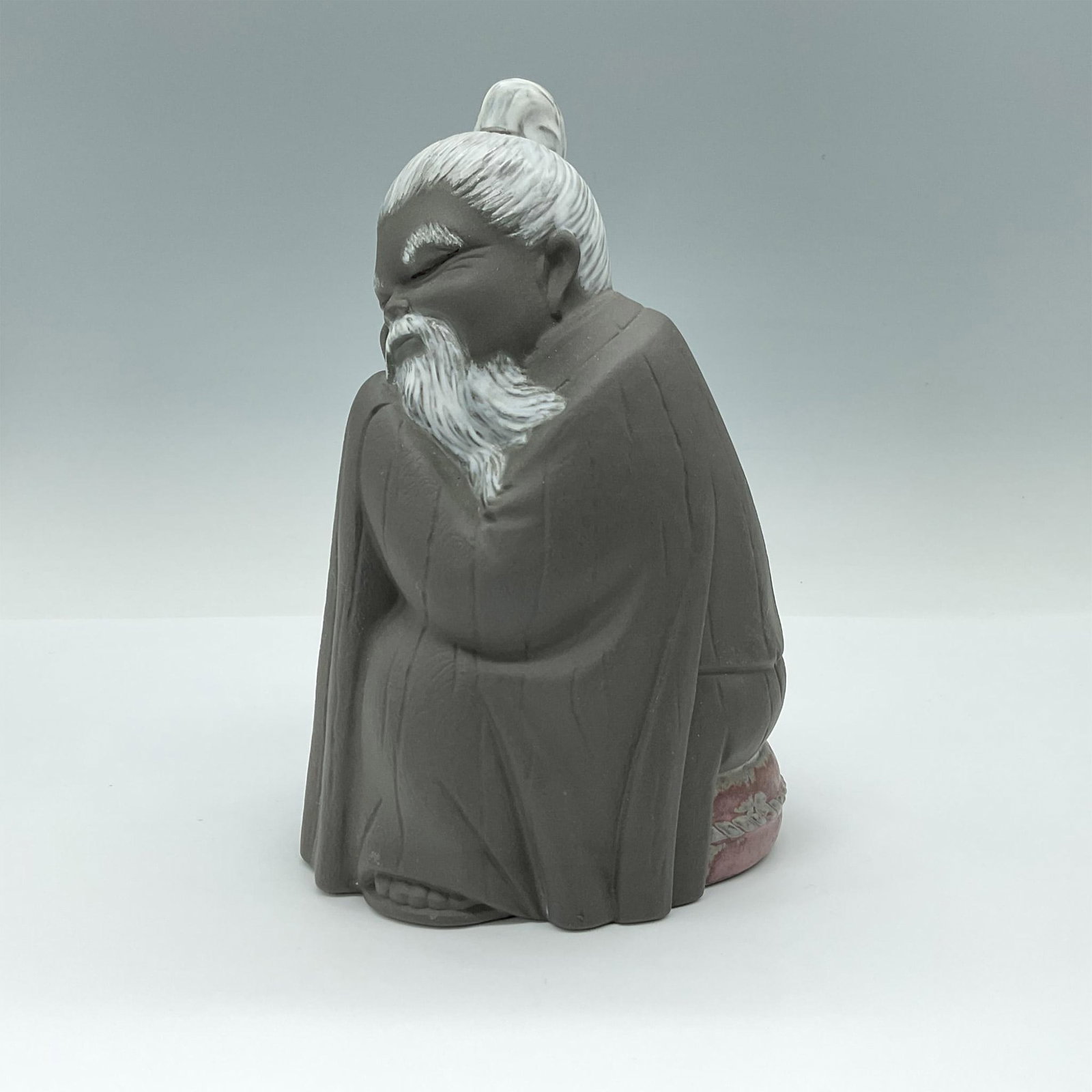 Lladro Porcelain Figurine, Short Chinese 1012057: Short Chinese man sitting, with long beard and bun. Lladro backstamp. Artist: Jose Roig Issued: 1974-2017 Dimensions: 4"L x 4.5"W x 7"H Manufacturer: Lladro Country of Origin: Spain