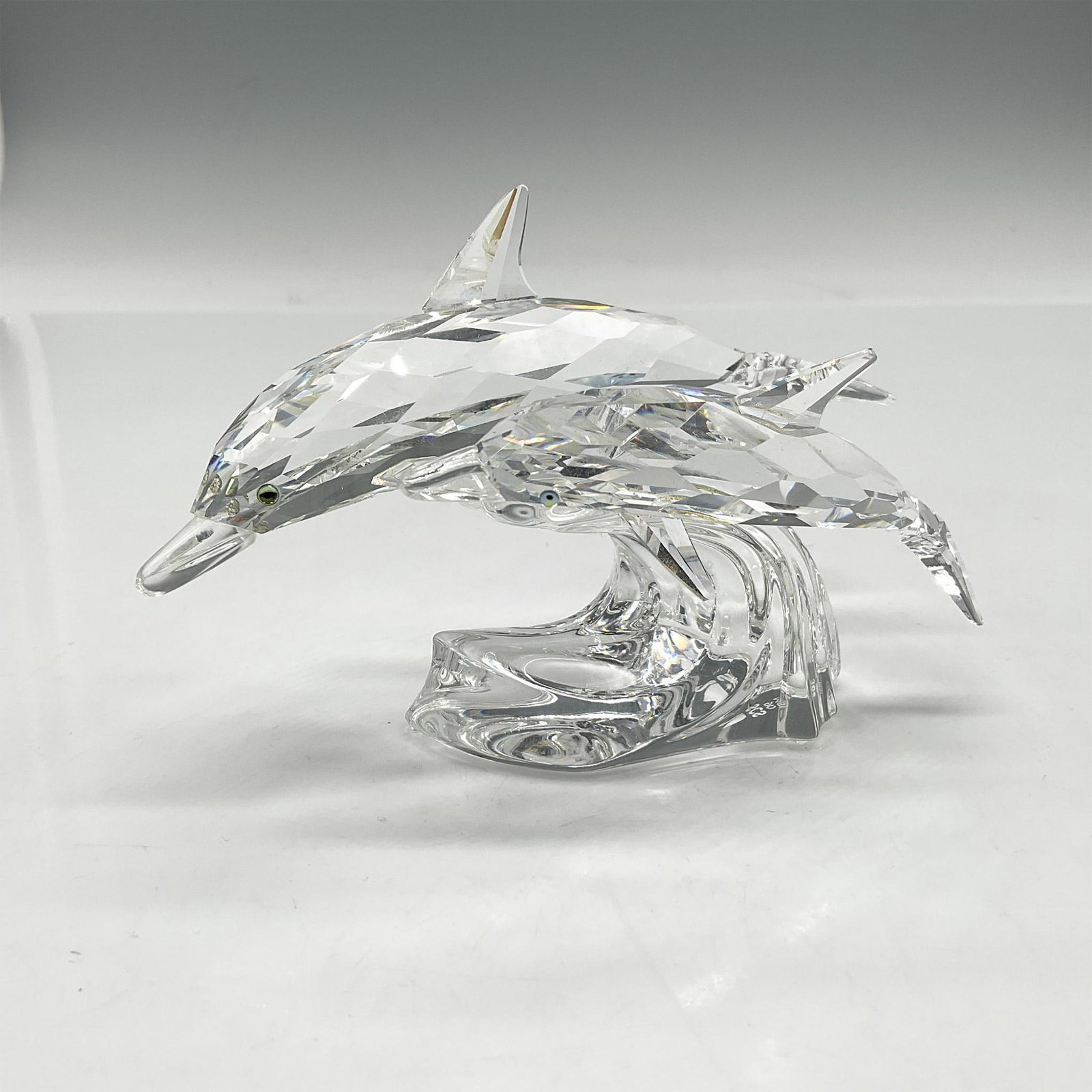 Swarovski SCS Figurines, 1990 Annual Edition Dolphin Lead Me: Second in the SCS trilogy of Mother and Child these figurals are made from clear crystal with azure eyes, swimming over a clear crystal wave. Swarovski backstamp. 153 850. Artist: Michael Stamey Issue