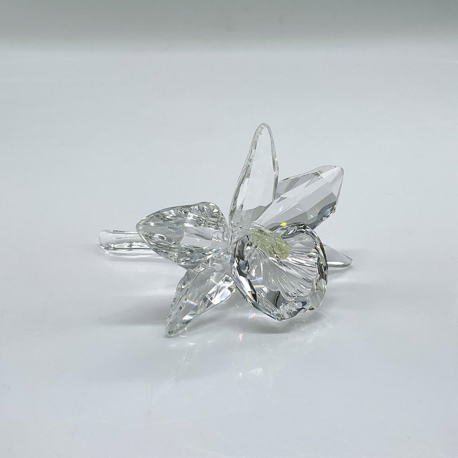 Swarovski Silver Crystal Figurine, Orchid With Yellow Pistil: Clear faceted crystal figure of an orchid with a light yellow pistil. Swarovski mark. Part of the Exquisite Accents collection. Issued: 1996-2000 Dimensions: 3"L x 2.5"W x 2"H Manufacturer: Swarovski 