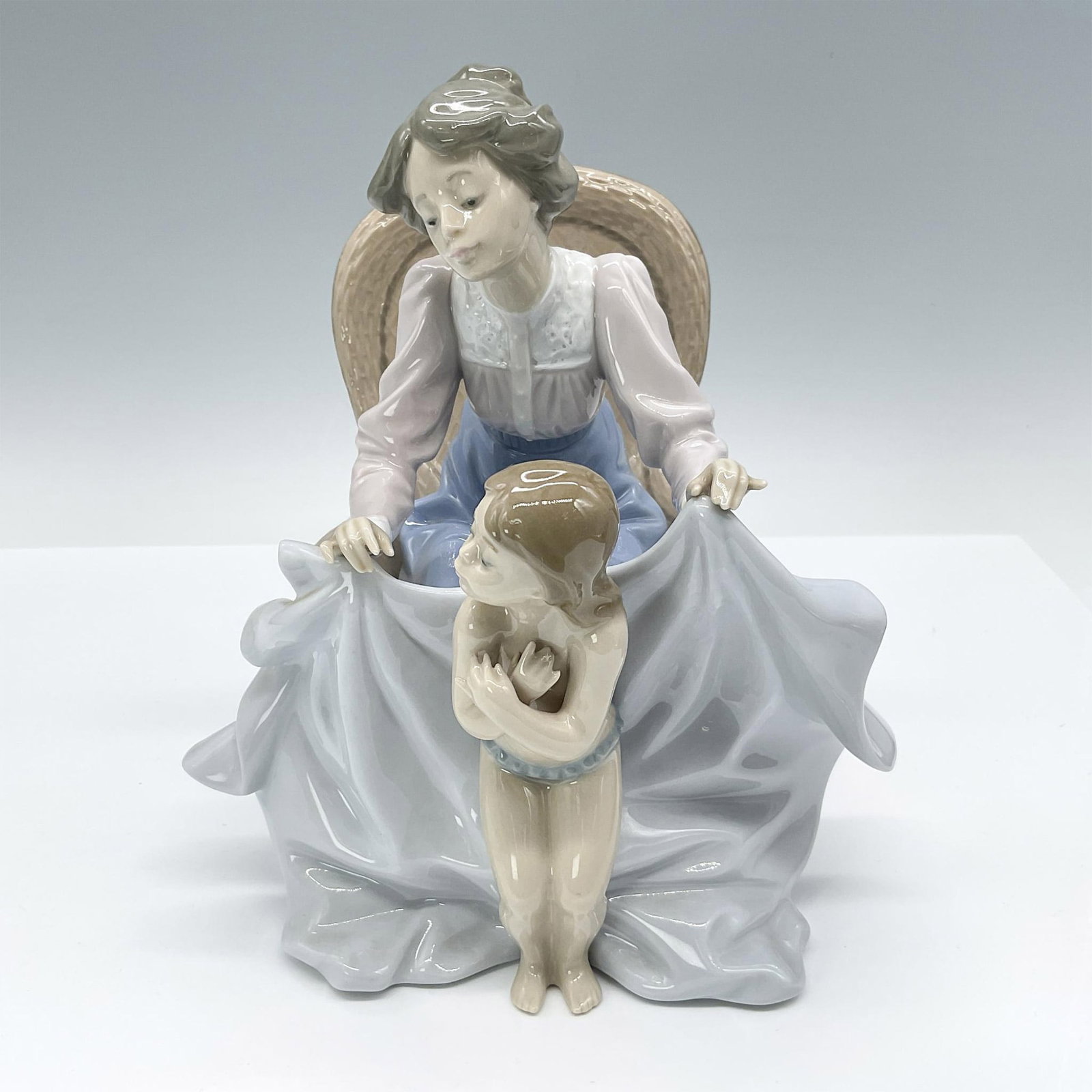 Mommy It's Cold 1005715 - Lladro Porcelain Figurine: Glossy figure depicting a mother tenderly wrapping her daughter in a towel or blanket. Lladro backstamp. Artist: Joan Coderch Issued: 1990-1993 Dimensions: 7"L x 7.5"W x 8"H Manufacturer: Lladro Coun