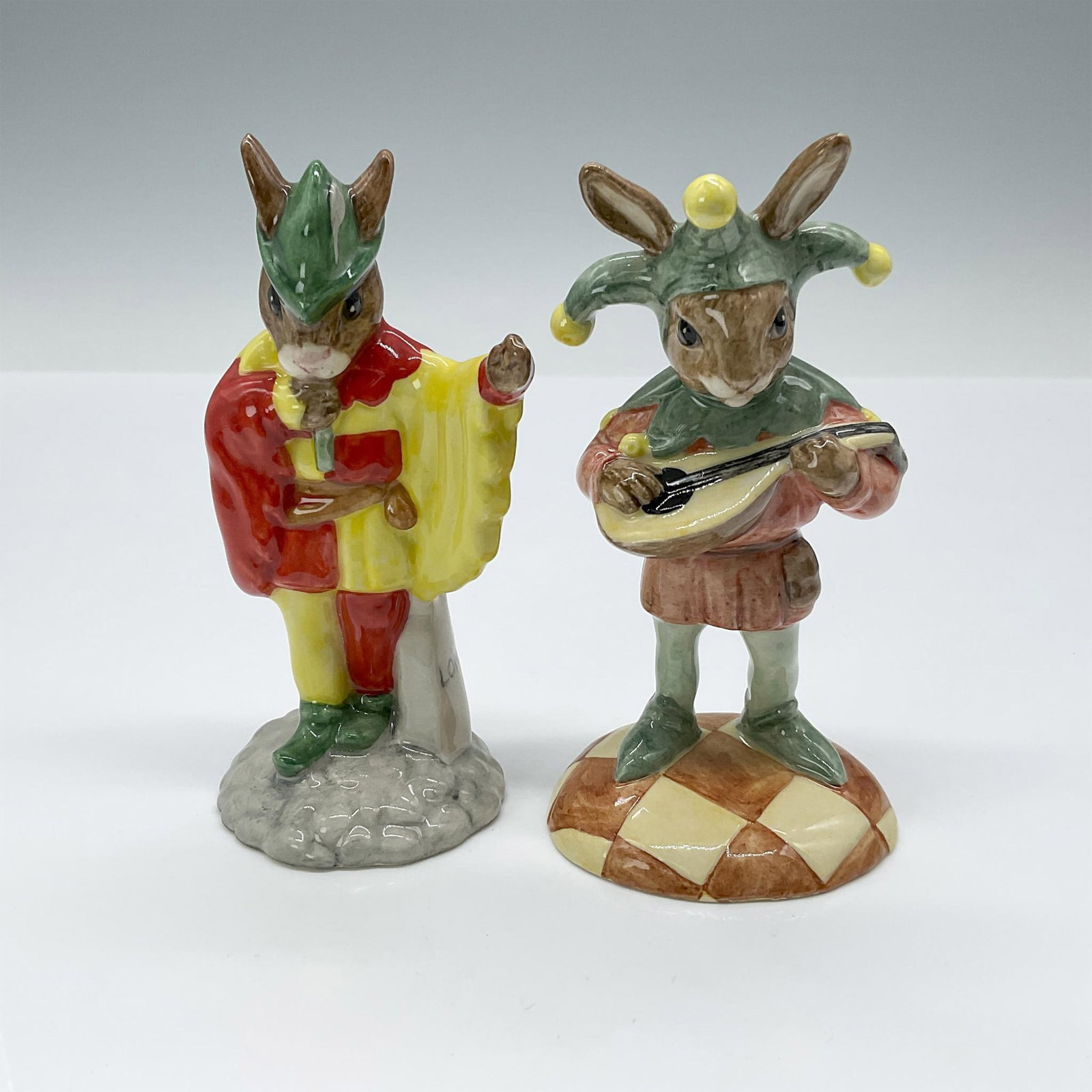 2pc Royal Doulton Bunnykins Figurines, Minstrel and Jester: Figurines include Jester DB161 and Minstrel DB211. Royal Doulton backstamp. Both figures similar in size with the larger piece measuring 2.25"L x 2"W x 4"H. Issued: 20th c. Edition Number: Minstrel 15