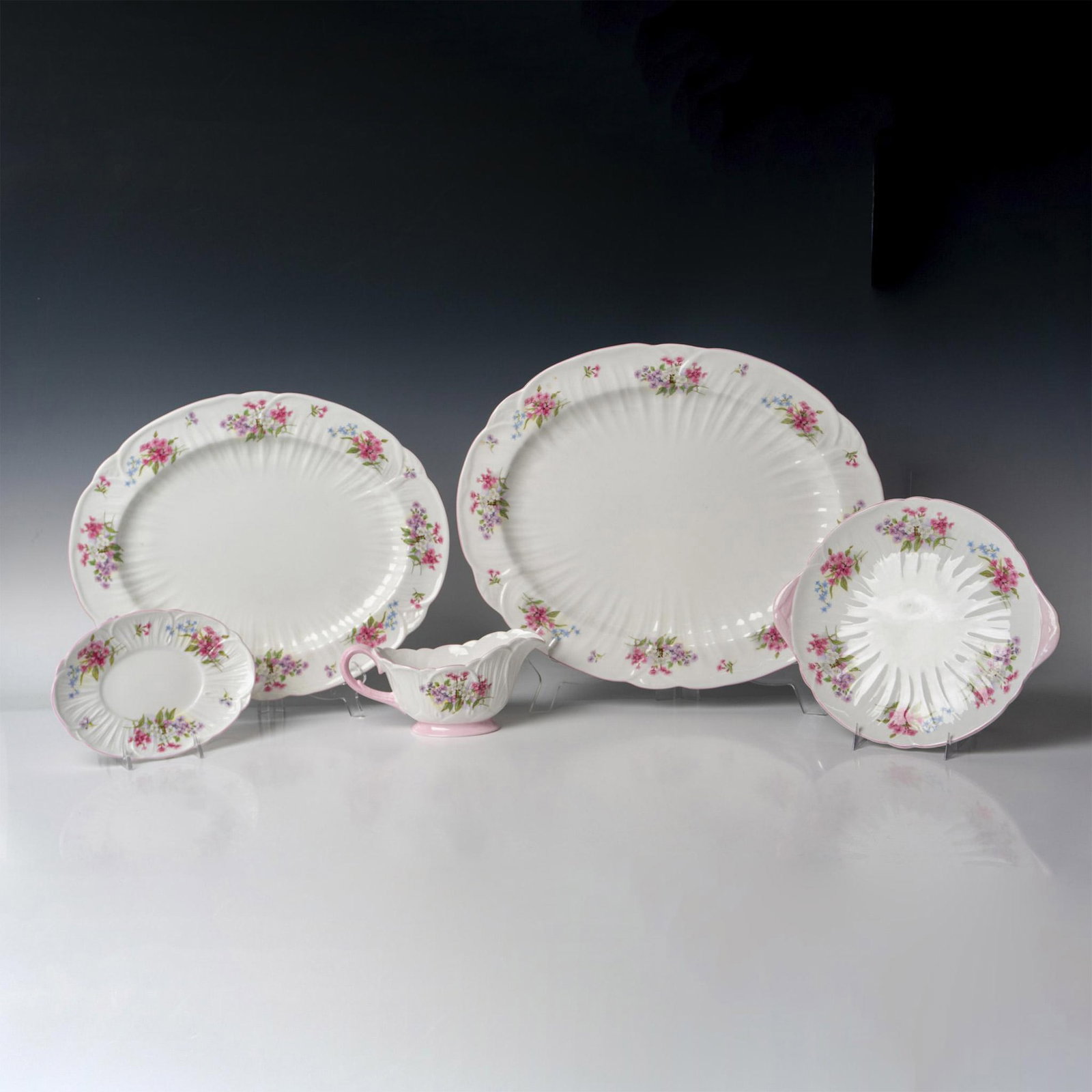5pc Shelley Bone China Serve Ware, Stocks: Dainty design of florals around edge with pink rim. Set includes large oval platter 17", medium oval platter 15", cake plate 10", oval underplate 7.5" and sauce boat 8". Shelley backstamp. 13428. Issu