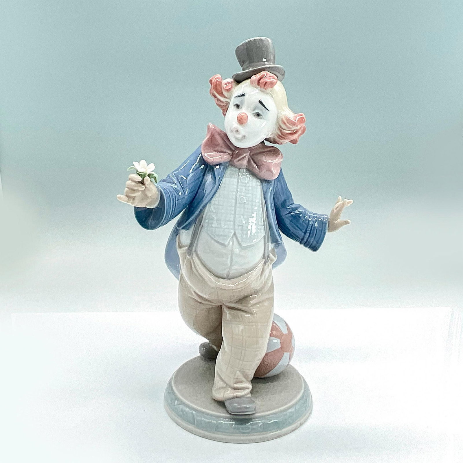 For A Smile 1006937 - Lladro Porcelain Figurine: Glossy finish; Lladro backstamp. Artist: Regino Torrijos Issued: 2003 - 2009 Dimensions: 9.5"H x 6.25"W Manufacturer: Lladro Country of Origin: Spain
