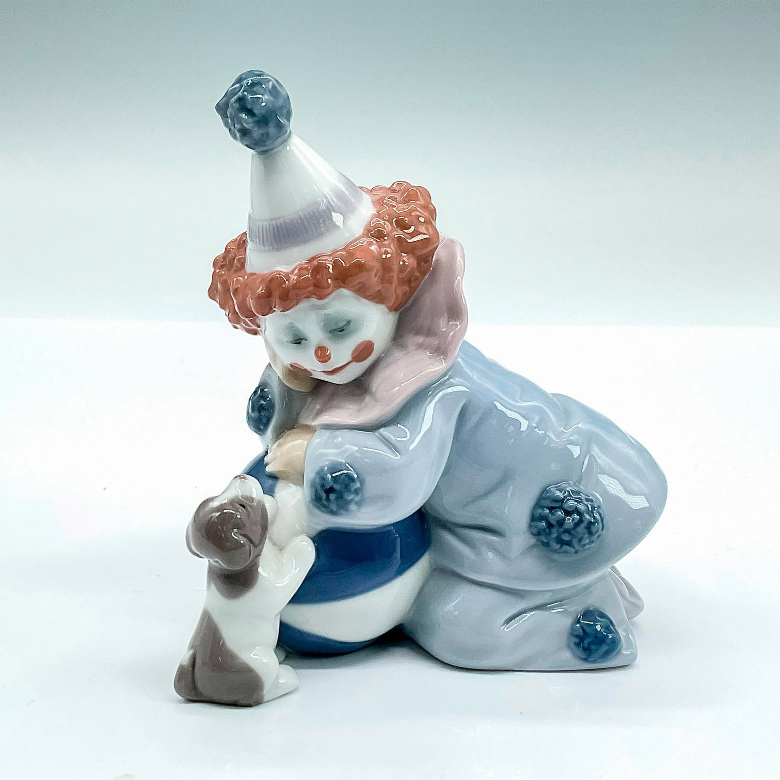 Pierrot with Puppy and Ball 1005278 - Lladro Porcelain Figurine: Glossy finish; Lladro backstamp. Artist: Jose Puche Issued: 1985 - 2007 Dimensions: 4"H x 4.5"W Manufacturer: Lladro Country of Origin: Spain