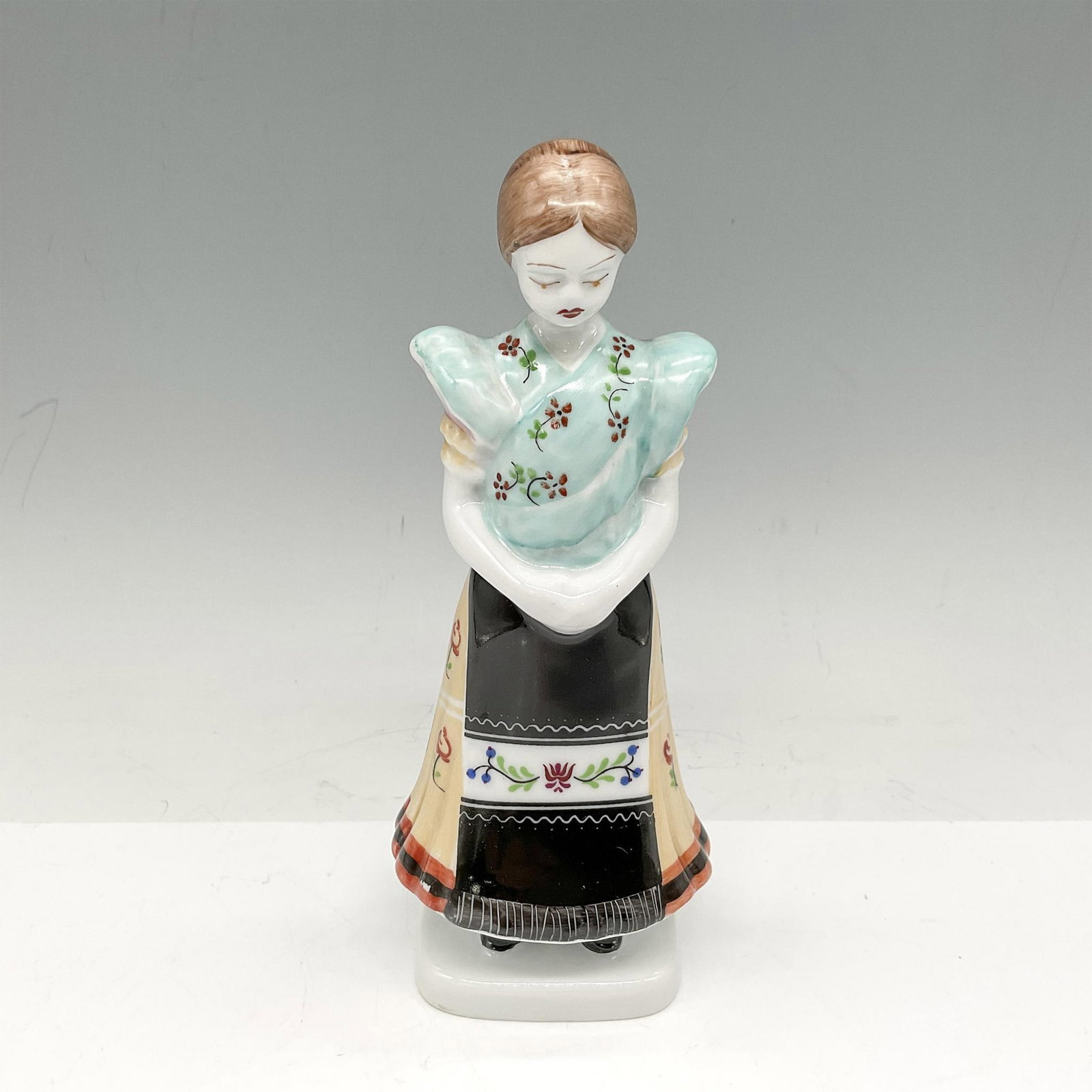 Holohaza Porcelain Figurine, Folk Figurine: Hand painted figural in traditional colorful dress. Holohaza backstamp. 1831. Issued: 20th century Dimensions: 3"L x 2.25"W x 6.75"H Manufacturer: Holohaza Country of Origin: Hungary