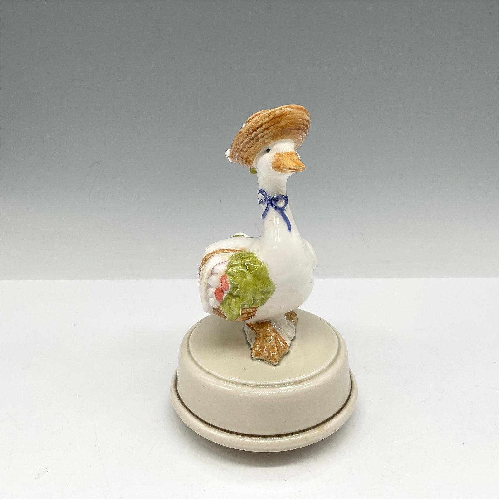Otagiri Porcelain Goose Music Box: Goose with hat holding her basket of vegetables. Music box plays Raindrops Keep Fallin on My Head. Otagiri backstamp. Issued: 20th century Dimensions: 6.5"H x 3.5" dia. Manufacturer: Ottagiri Country 