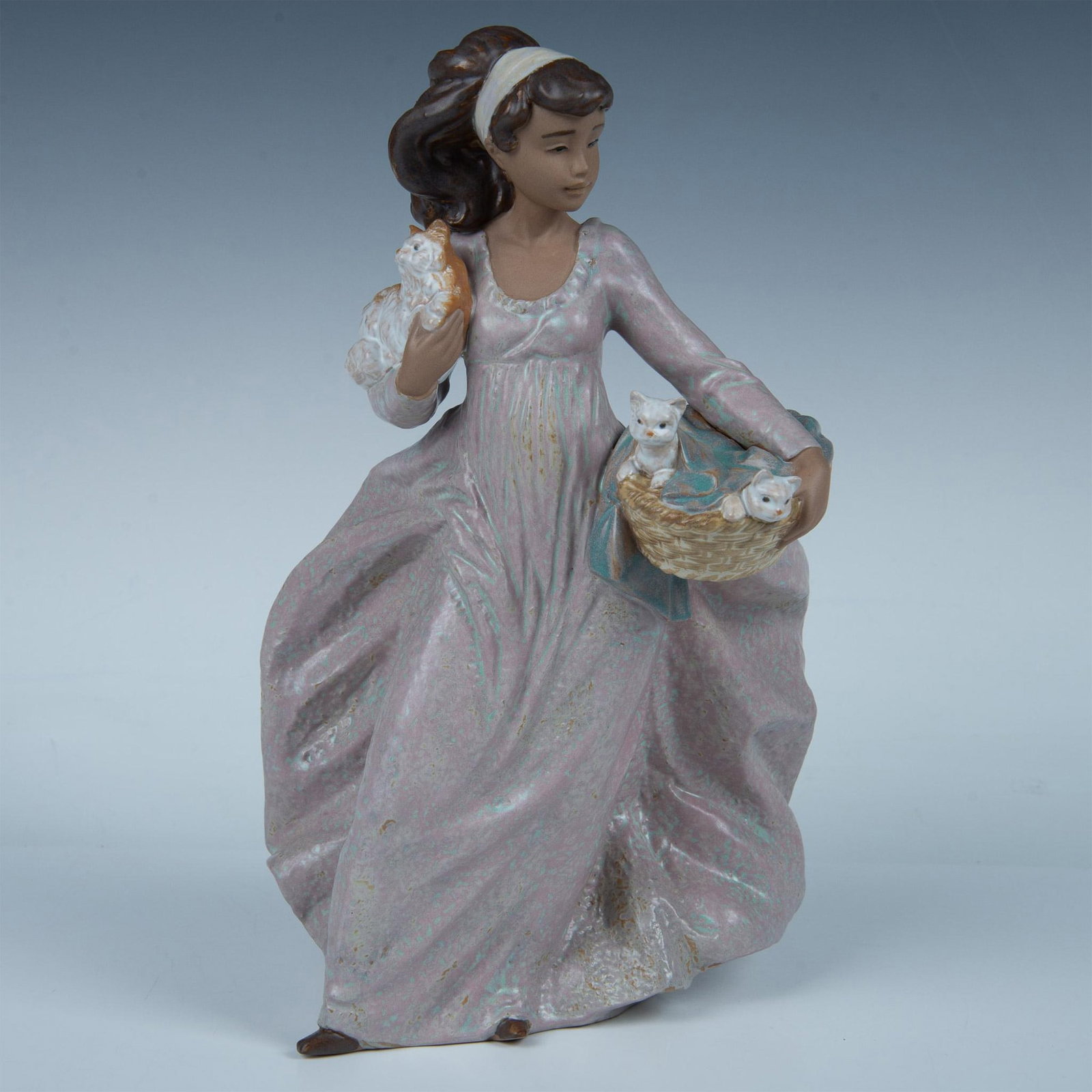 Basket of Fun 1012324 - Lladro Porcelain Figurine: Lovely young girl holding kittens in basket and mother cat in her arm. Lladro backstamp. Artist: Regino Torrijos Issued: 1995 - 2001 Dimensions: 7.5"L x 7"W x 11.75"H Manufacturer: Lladro Country of