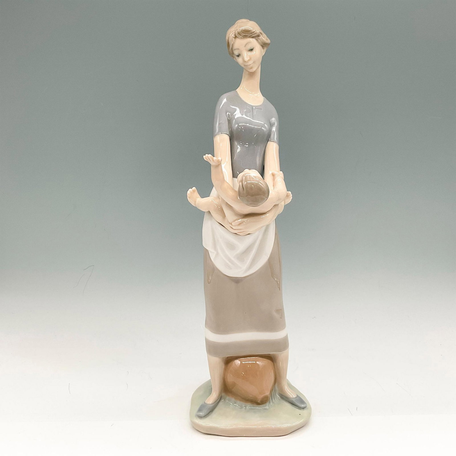 Mother and Child 1004575 - Lladro Porcelain Figurine: Glossy figural colored in soft grey and tan, holding her baby at arm's length. Lladro backstamp. Artist: Fulgencio Garcia Issued: 1969 - 1997 Dimensions: 4"L x 4"W x 13"H Manufacturer: Lladro Country