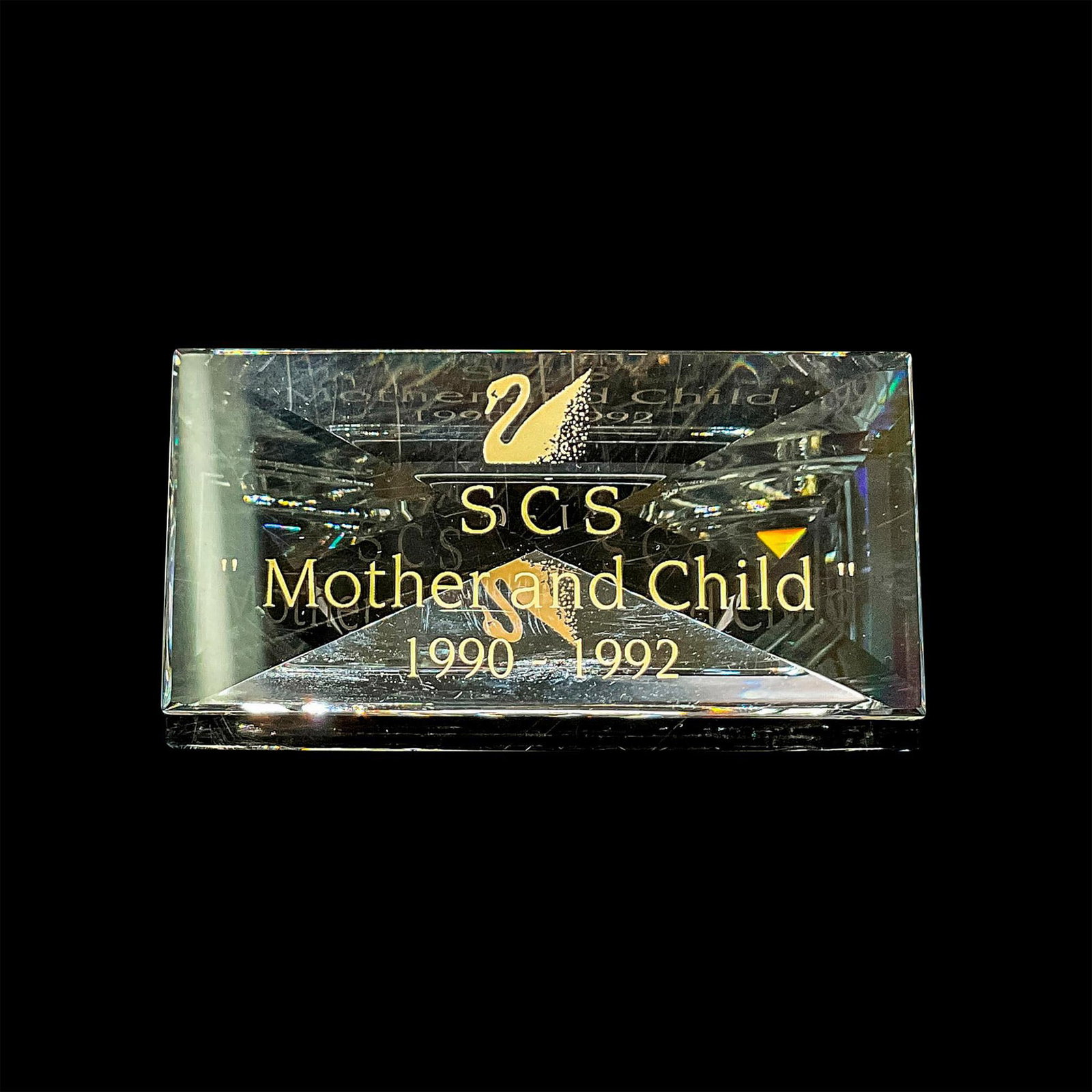 Swarovski Crystal SCS Mother and Child Display Plaque: Swarovski Collector Society clear crystal display sign for Mother and Child figurines. This item has its original box: 5"H x 3.25"dia. Issued: 1990-1992 Dimensions: 2.75"L x 1"W x 1"H Manufacturer: Sw