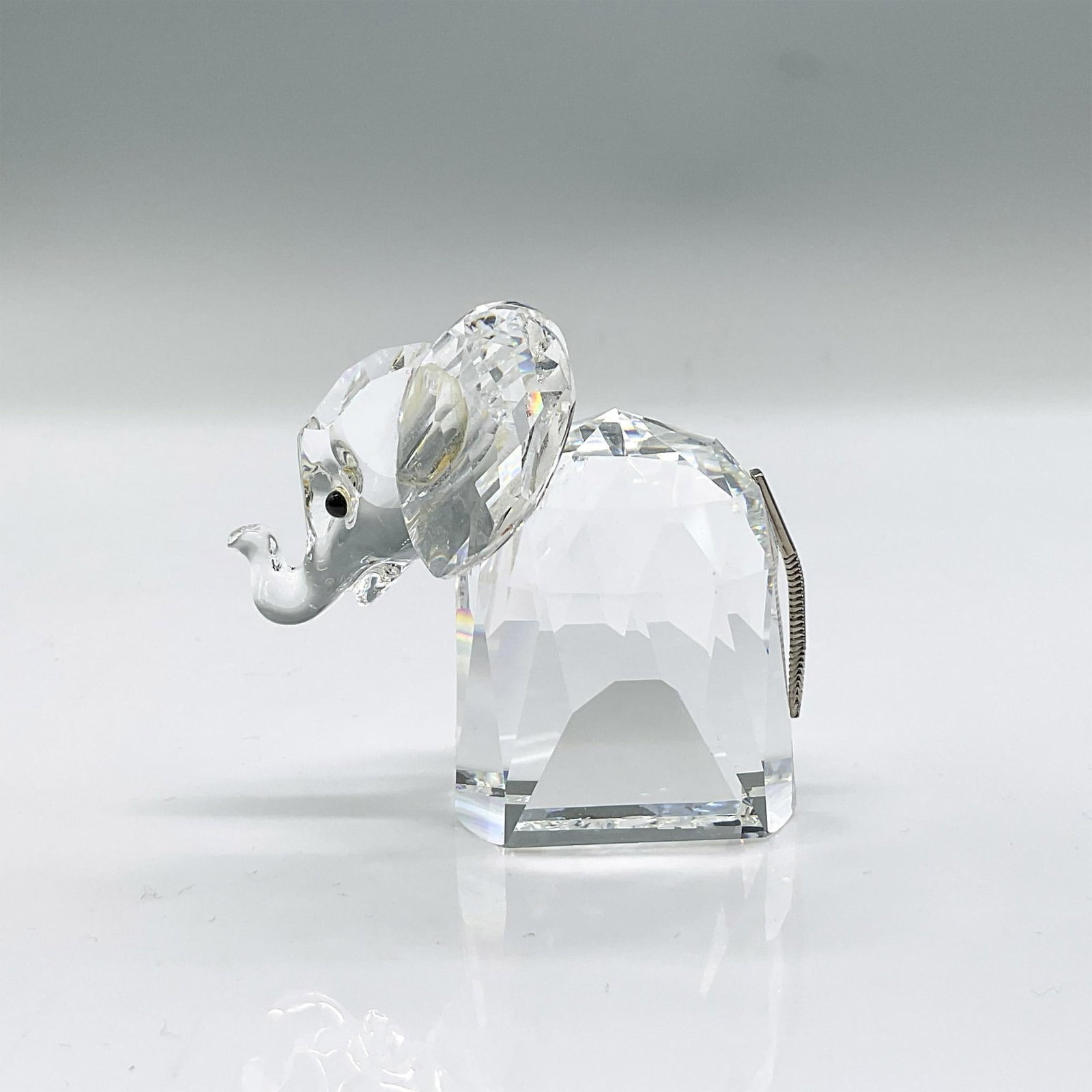 Swarovski Crystal Figurine, Elephant: Clear faceted crystal figure of an elephant with black eyes and metal tail. Part of the African Wildlife collection. Swarovski mark. Issued: 1982-1989 Dimensions: 2.5"L x 1.5"W x 2.25"H Manufacturer: 